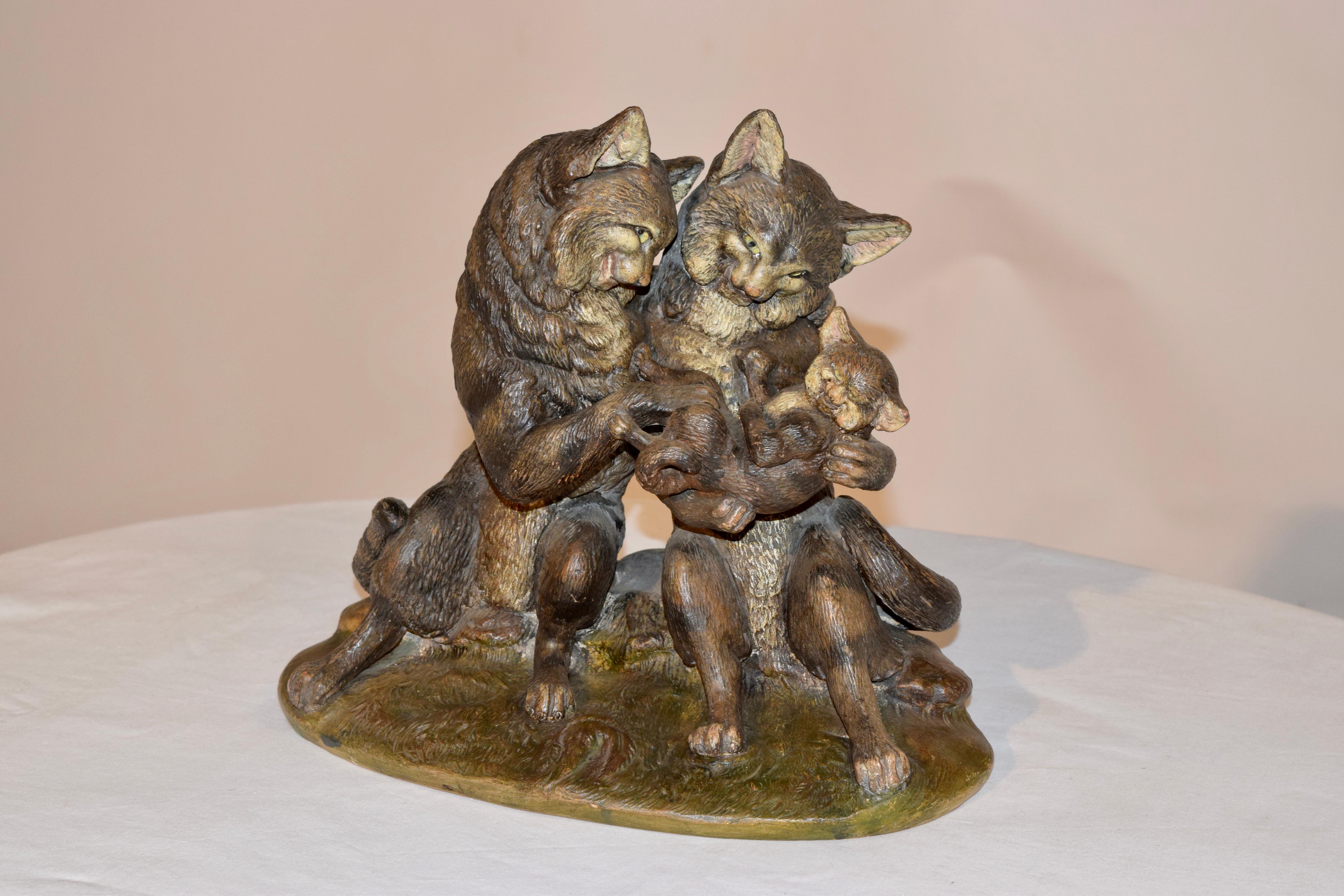 19th century Austrian figural group of a family of cats. The group has been cold painted and has vibrant coloring. The male and female cats have striped coats and glass eyes, and are depicted holding a baby cat, as they look on adoringly. They