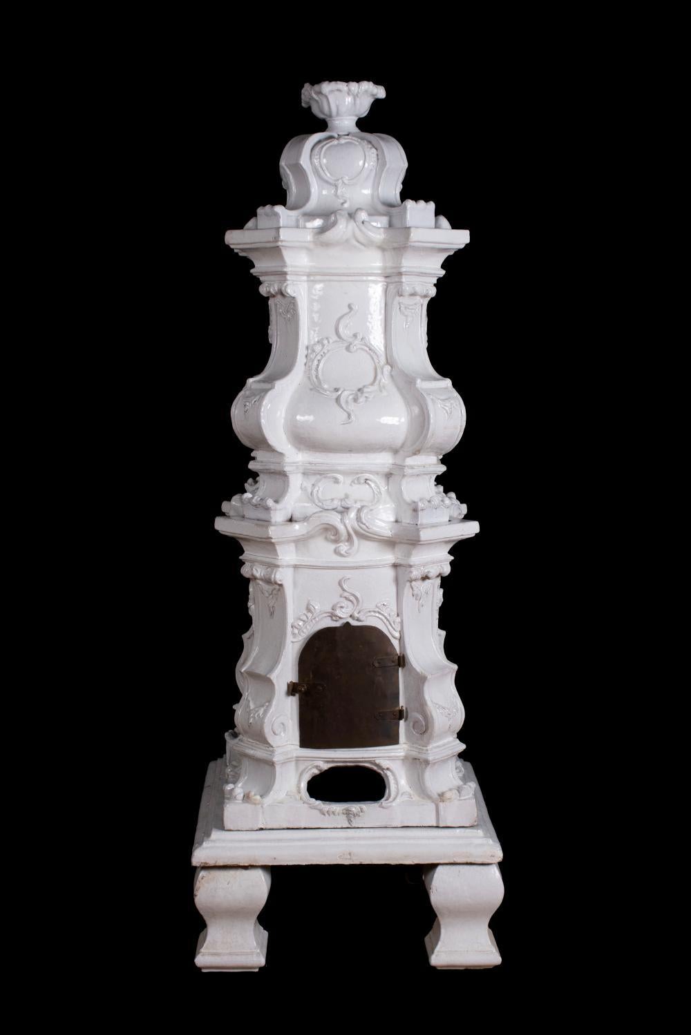 Estufa austriaca de baldosas de terracota blanca o Kachelofen.  Mediados del siglo XIX en estilo rococó.  Varias piezas con puerta de carga de hierro y respiradero.  En buen estado, sólo pequeños desconchones.  En nueve secciones.