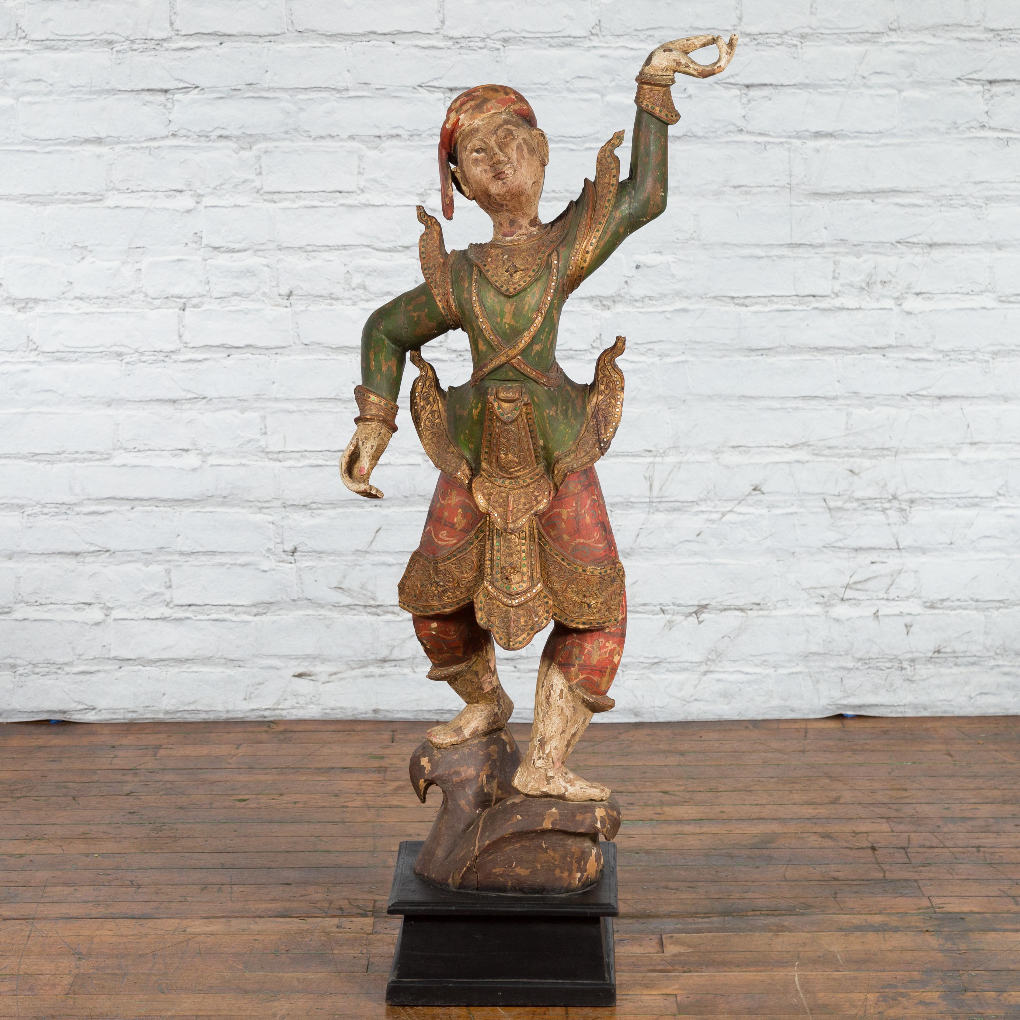 A tall antique Balinese hand-carved and painted wooden statue from the 19th century on black base. Hand-made on the island of Bali, Southern Indonesia during the 19th century, this wooden sculpture captures our attention with its lively attitude and