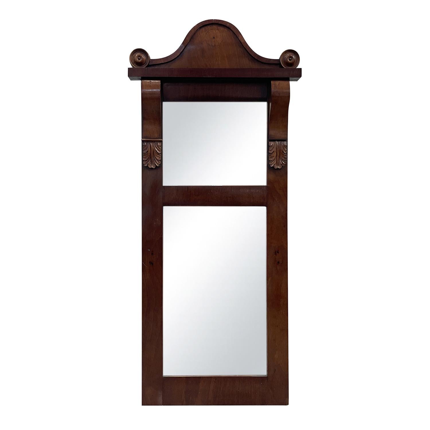 An antique Baltic wall mirror made of hand crafted polished Mahogany, in good condition. The 19th Century mirror contains the original two-part mirrored glass, particularized by detailed wood carvings. Minor fading, due to age. Wear consistent with