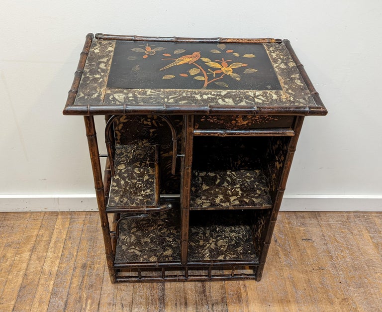 19th century hall table also called Half Table. Bamboo construction with embossed paper lacquered to the wooden flats that make up the shelfs and walls. Chinoiserie style painting to the top, open on the left side with bamboo details having one