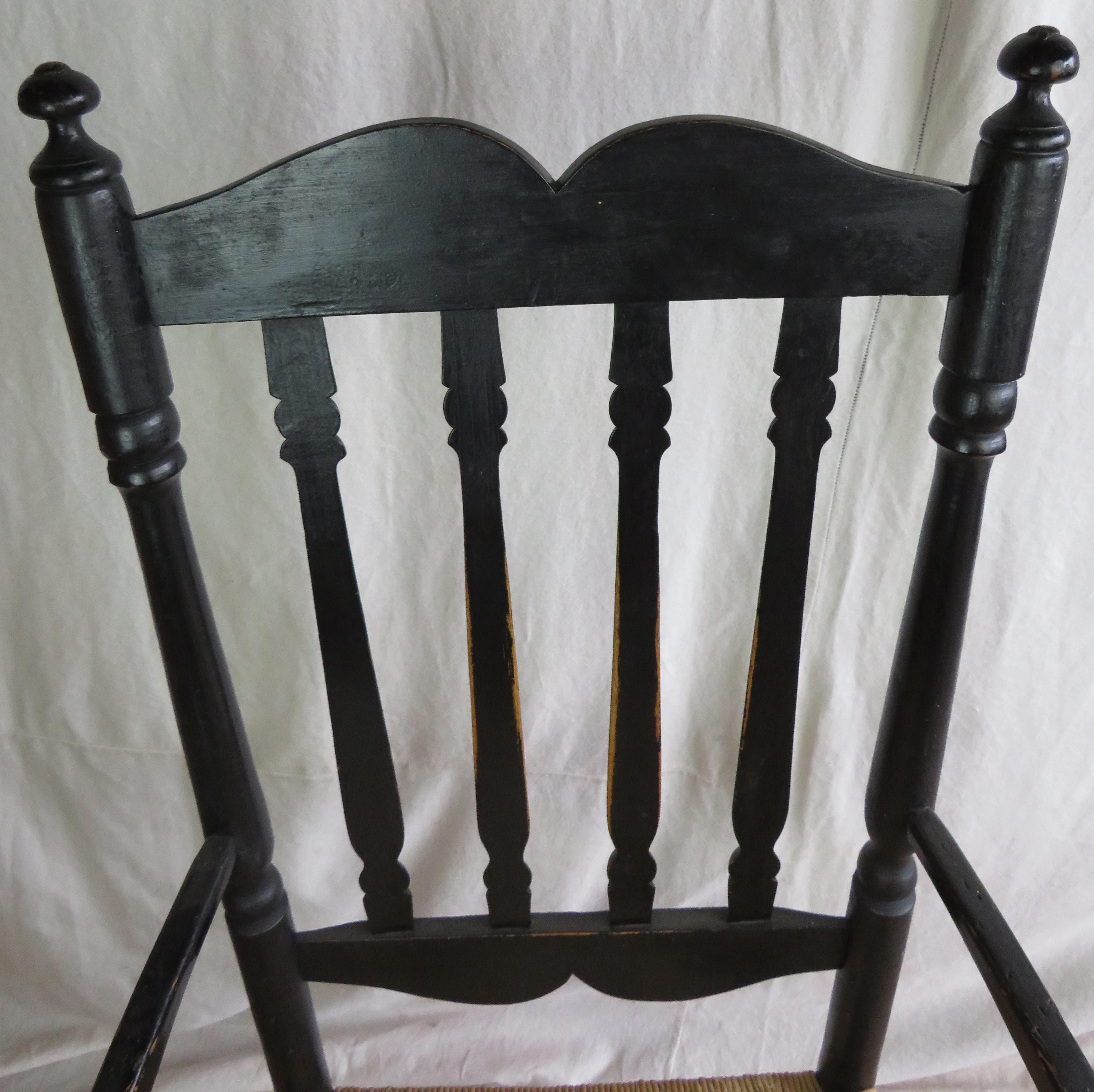 19th century American Bannister Back armchair in black paint with nicely turned features, rush seat with damage to left edge of seat.