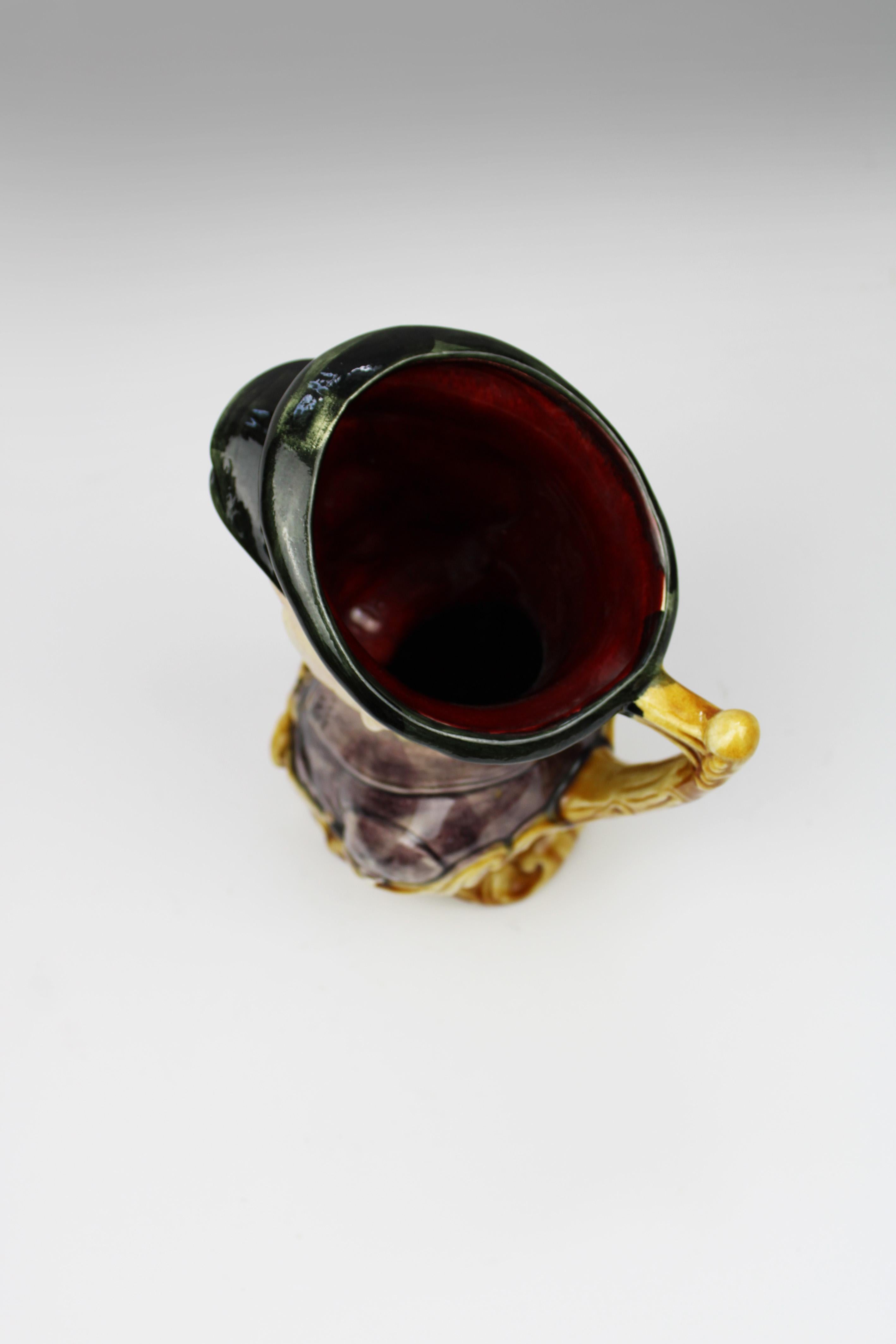 Ce rare pichet à eau en majolique de Barbotine du XIXe siècle, représentant un chef de gare ou un cheminot, est une pièce remarquable d'Onnaing, France. Ce pichet, qui illustre l'artisanat vibrant et complexe de la majolique de Barbotine, se