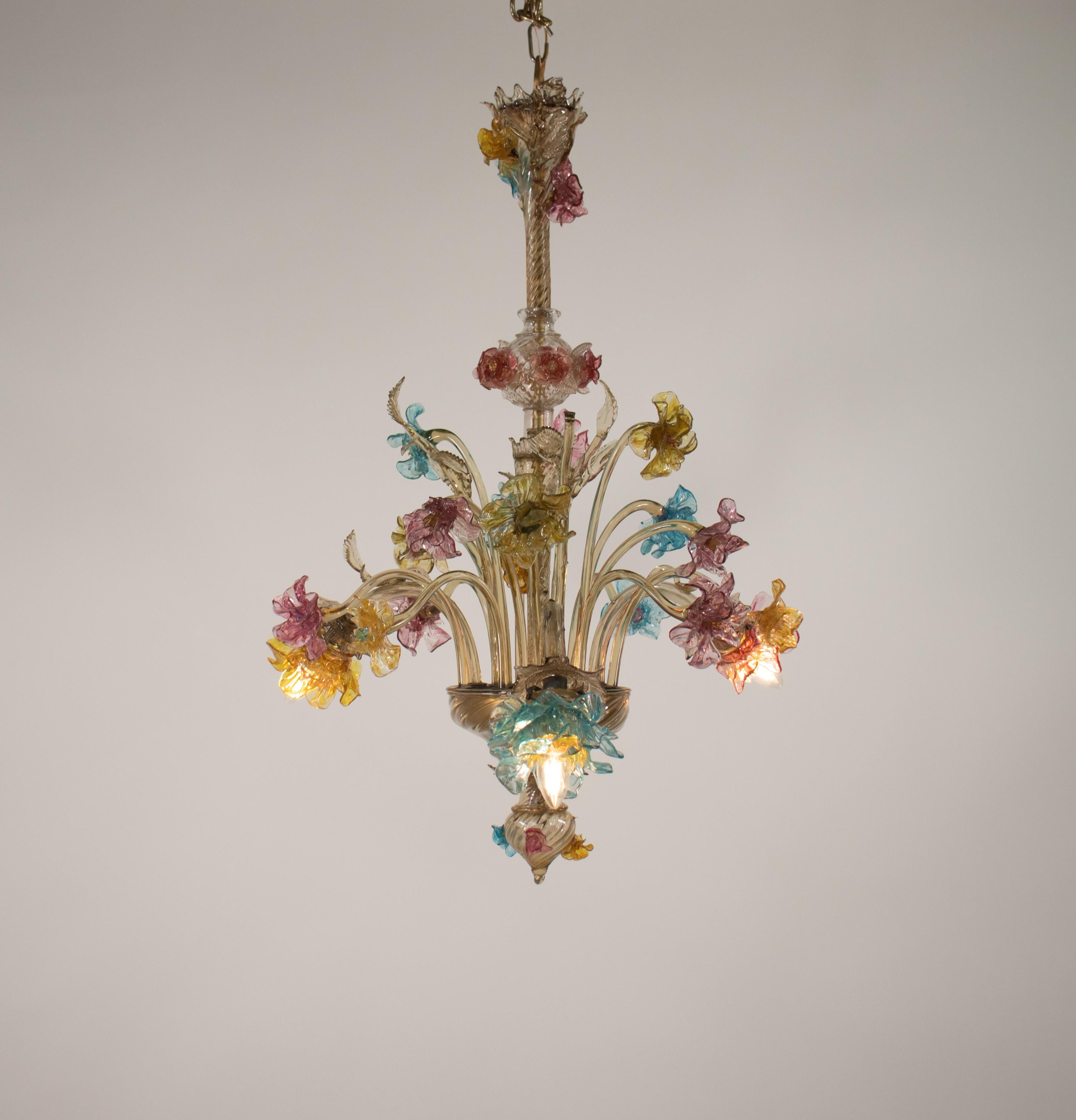 Cet exquis lustre floral multicolore en verre de Murano du XIXe siècle comporte trois lumières déguisées par une cascade de fleurs et de feuilles, évoquant un jardin sauvage. La colonne centrale est ornée d'une volute, d'un globe décoratif et d'une