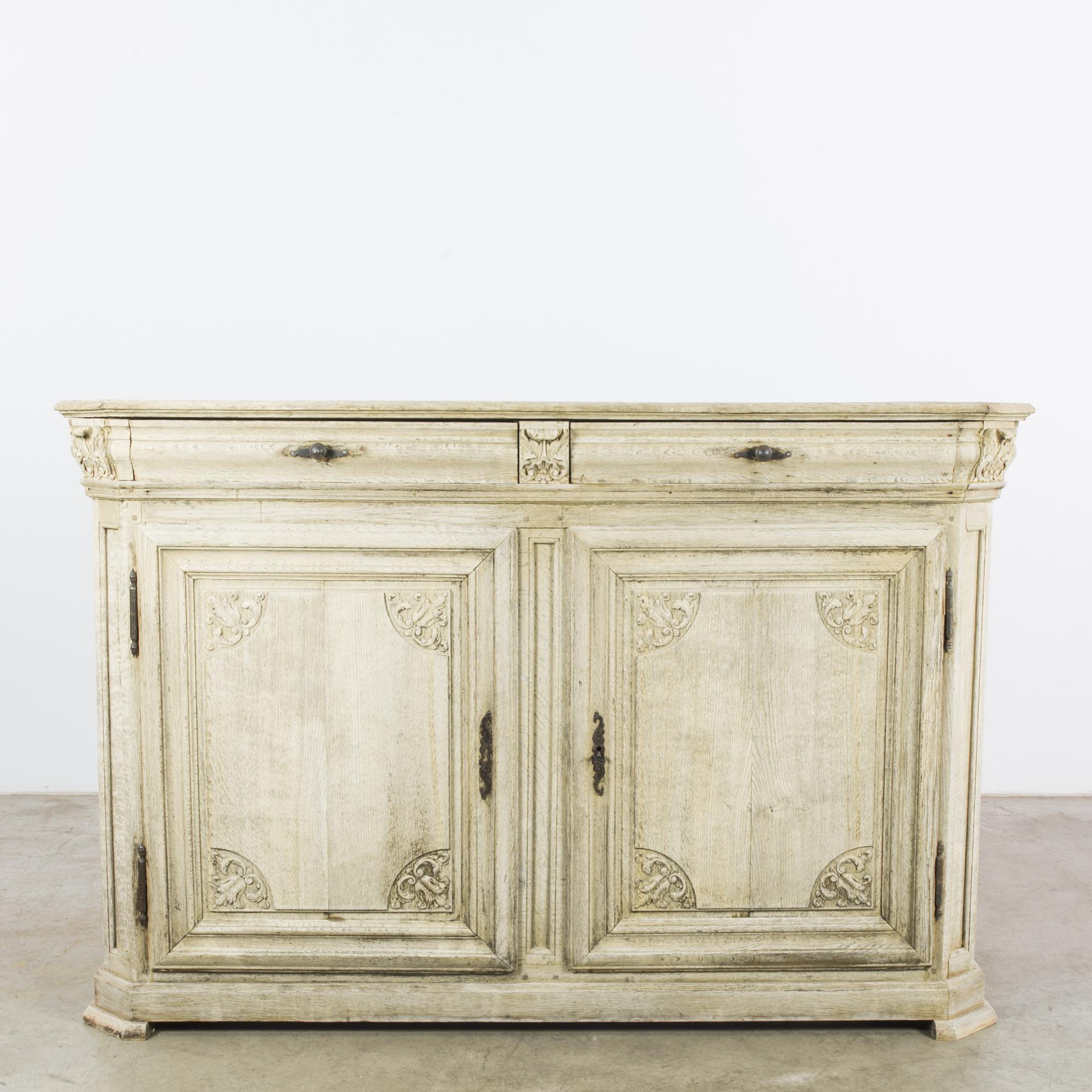 An oak buffet from Belgium, circa 1800. Exquisitely detailed carving adds a baroque touch to the contoured cabinet. Little flowers peek from between leafy flourishes and shell-like crests. Original lock pieces and drawer handles echo sinuous lines.