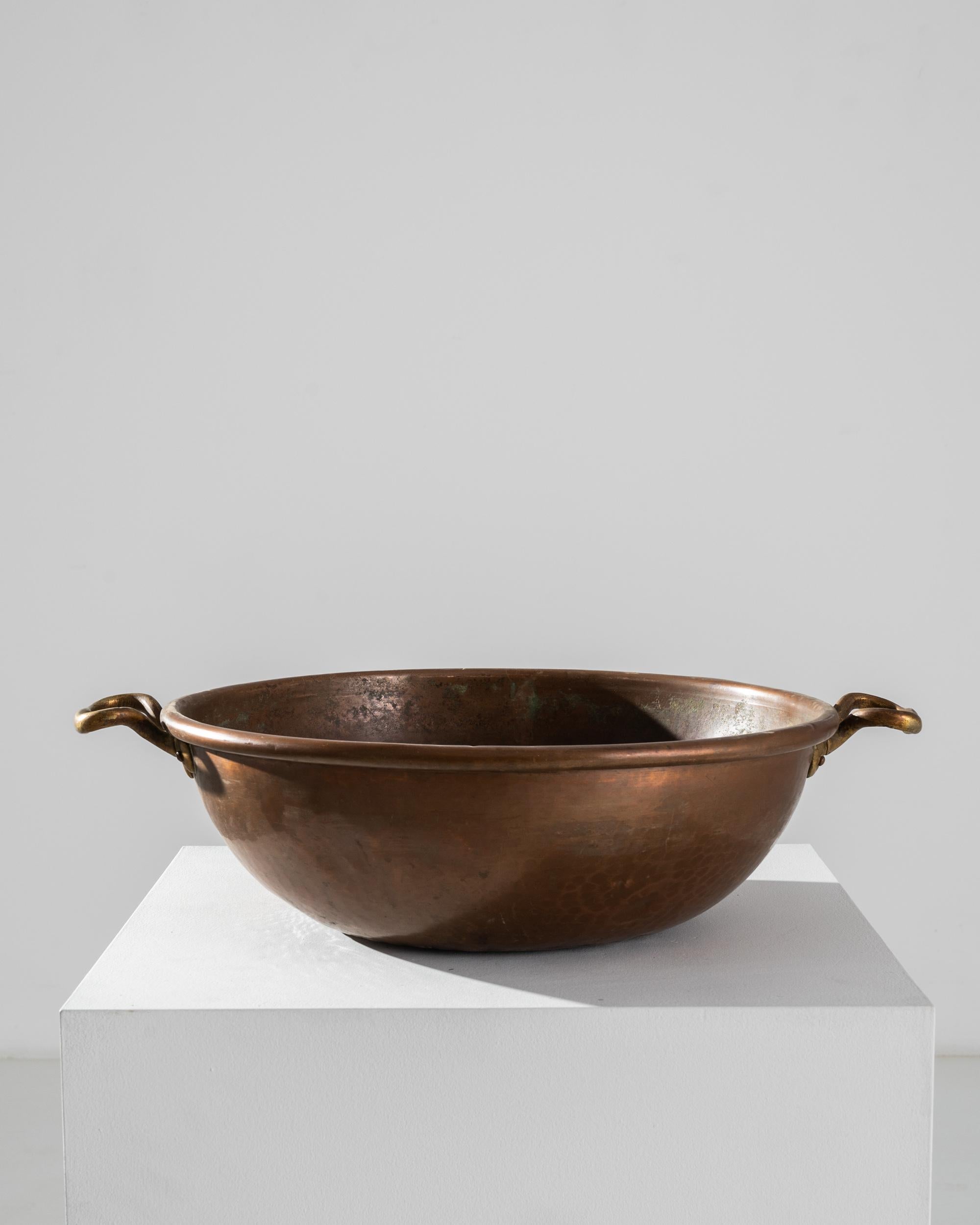 A copper bowl from 19th century Belgium. One of the best metals for conducting heat evenly, copper has been used for sauces, jams and marmalade making for centuries. A round shape, with upraised handles; the rich, rosy tone of the metal brings a
