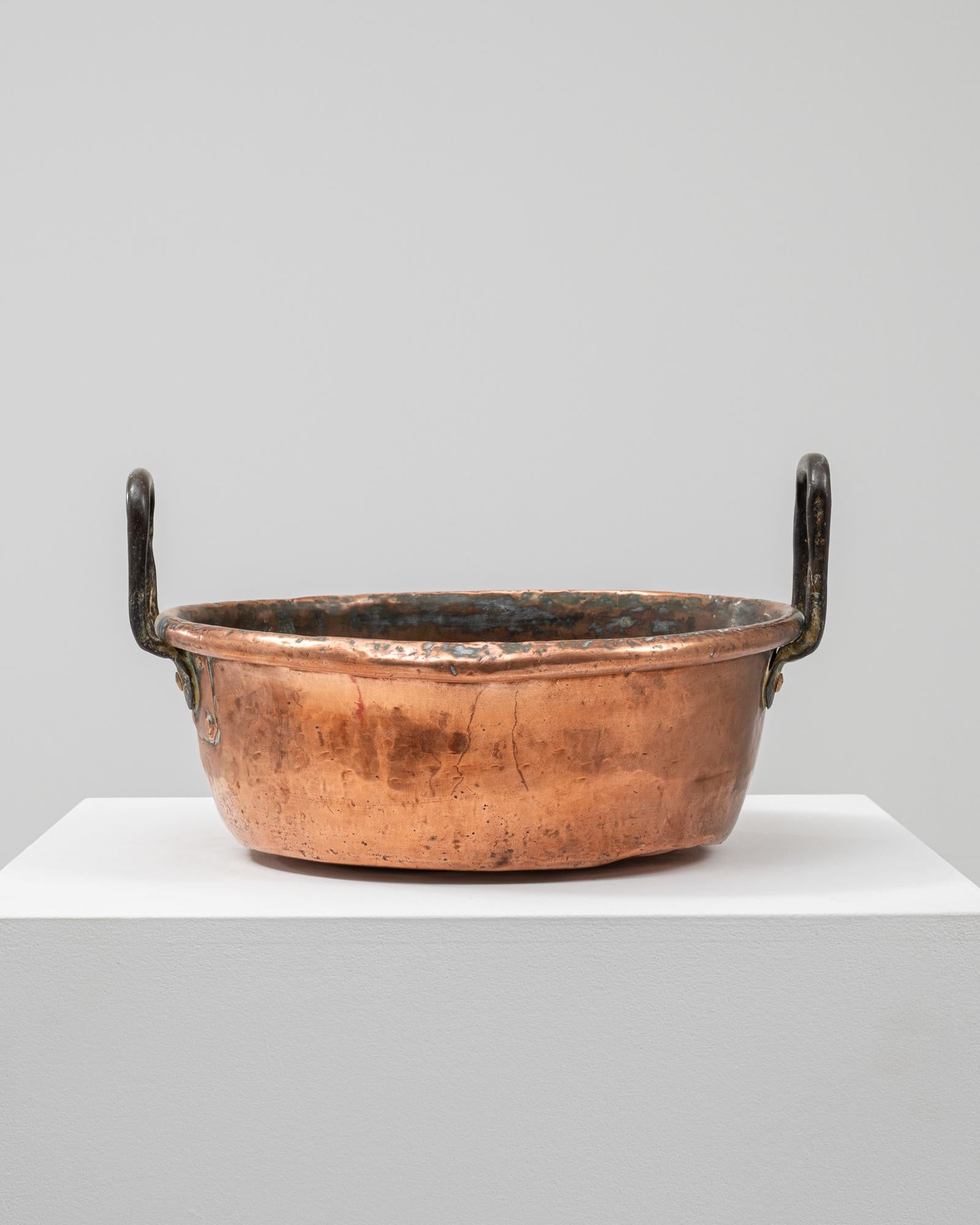 This 19th-century Belgian copper pot exemplifies traditional European metalwork with its hand-hammered surface and aged patina. Crafted from solid copper, it features substantial side handles forged from iron, designed for durability and ease of use