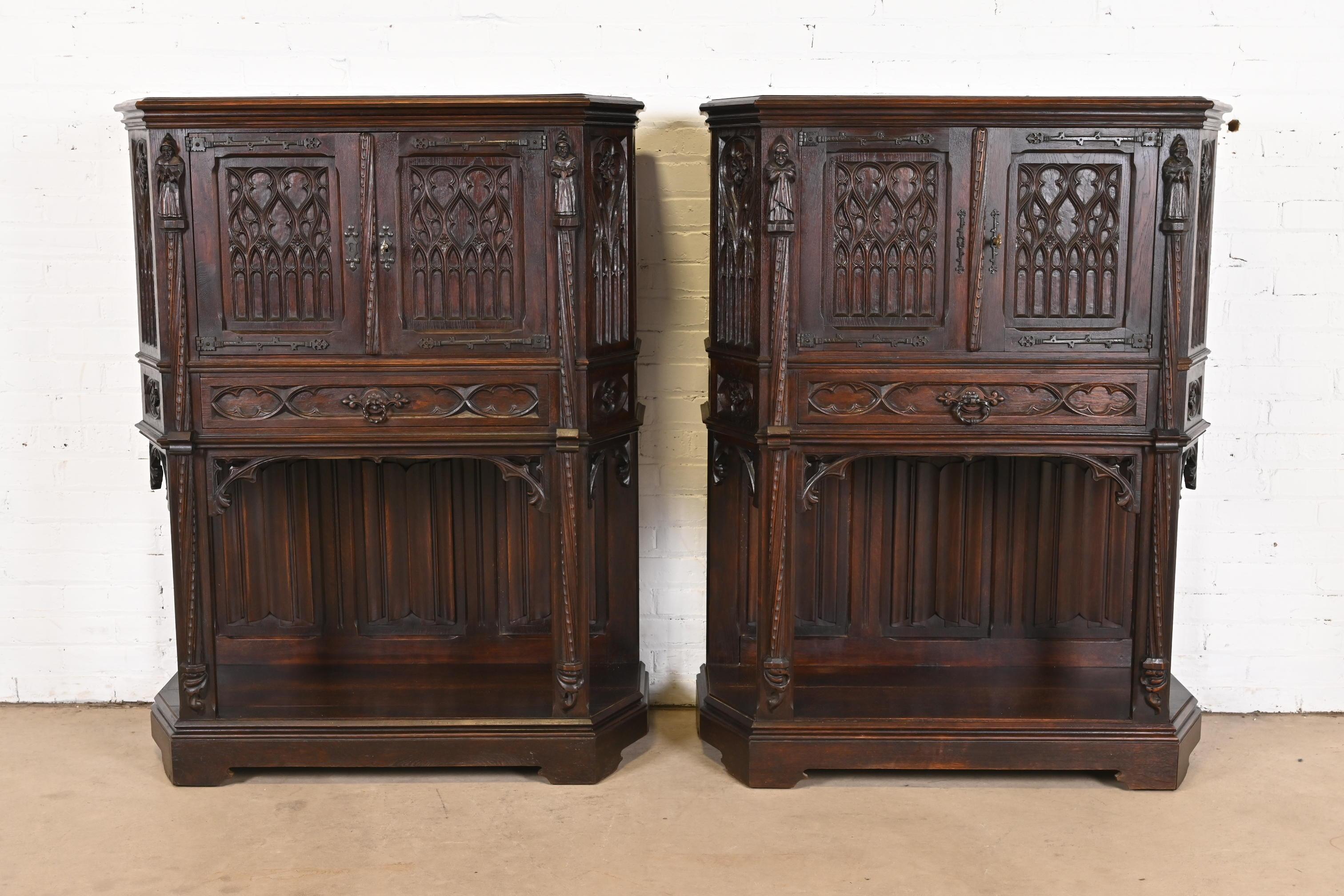 A gorgeous pair of antique Gothic or Renaissance Revival bar cabinets

In the manner of R.J. Horner

Belgium, Circa Late 19th Century

Carved dark oak, with original iron hardware.

Each measures: 39.25