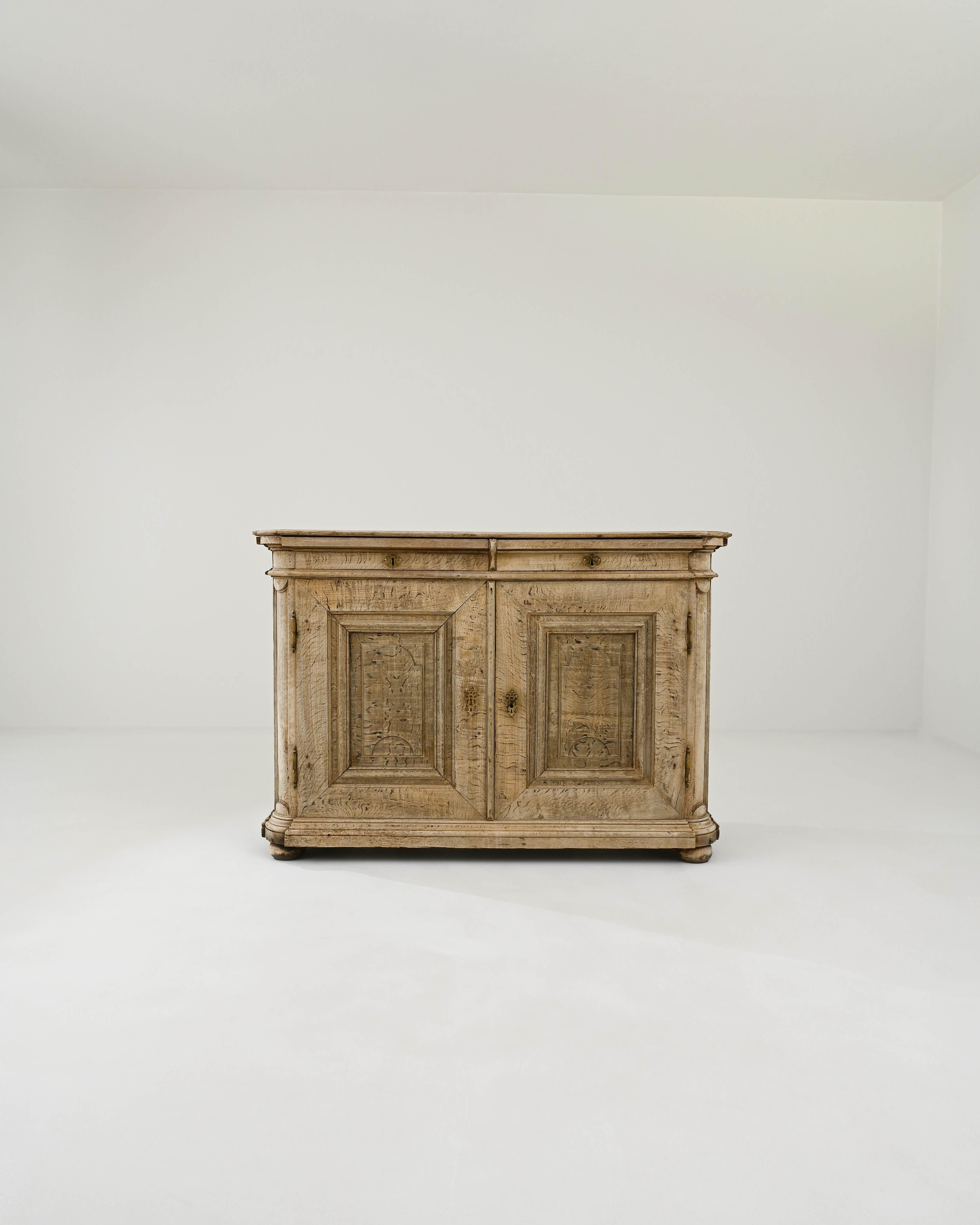 Timeless craftsmanship and the beautiful finish of the natural oak make this antique buffet a find to treasure. Hand-built in France in the 1800s, discreet decorative accents bring personality to the spacious cabinet. The half-moon details of the