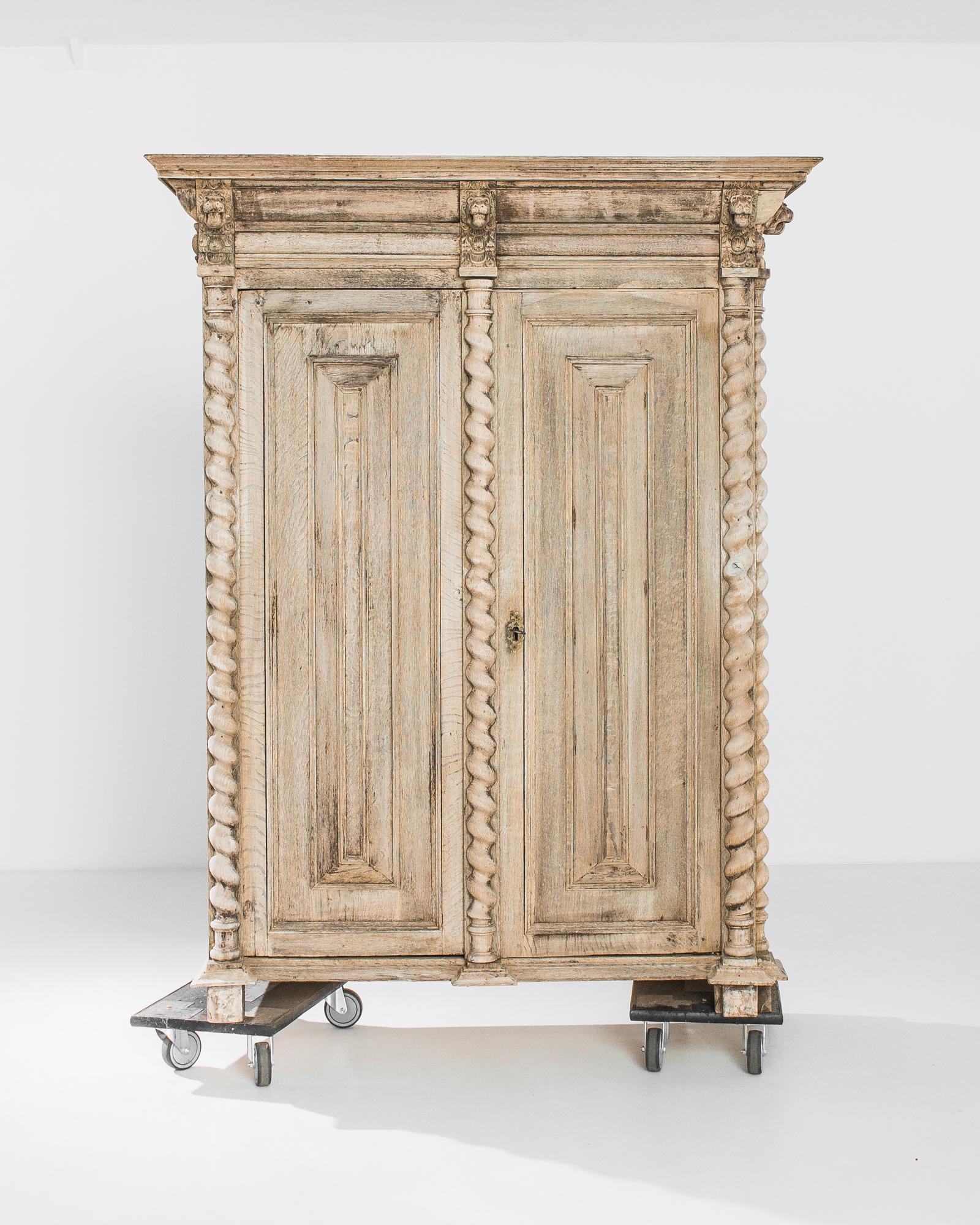 Like a centuries old antique column, this oak cabinet made in Belgium circa 1860 inspires a commanding presence. The exterior is solemnly adorned by lion mask carvings on the top and spiral pillars, which give an effect of a subtle flow. The