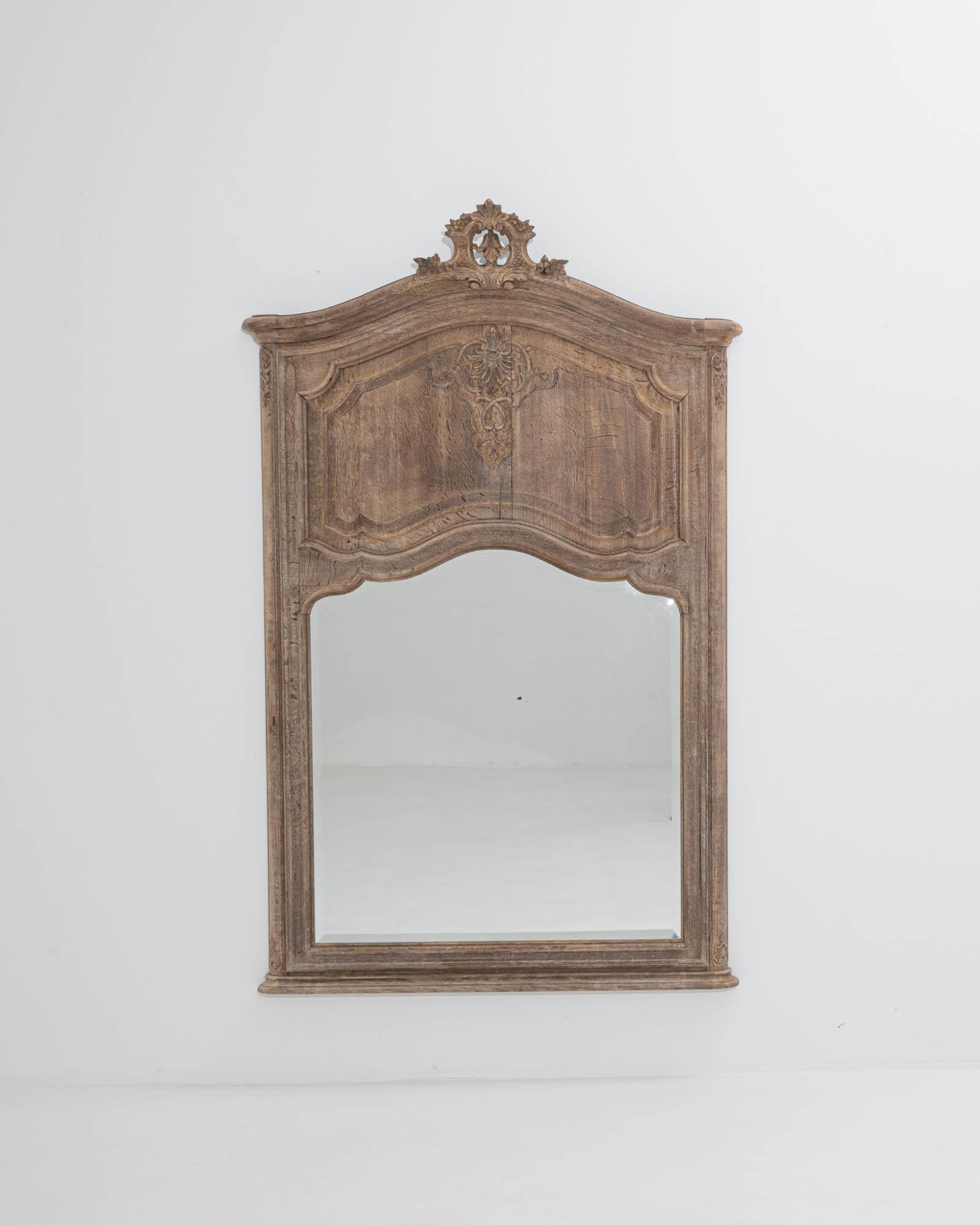 An elegant Baroque shape and intricate carvings give this antique mirror an enchanting personality. Made in Belgium in the 1800s, the surface of the oak has been carefully restored in our workshops to reveal a mellow natural hue with blush