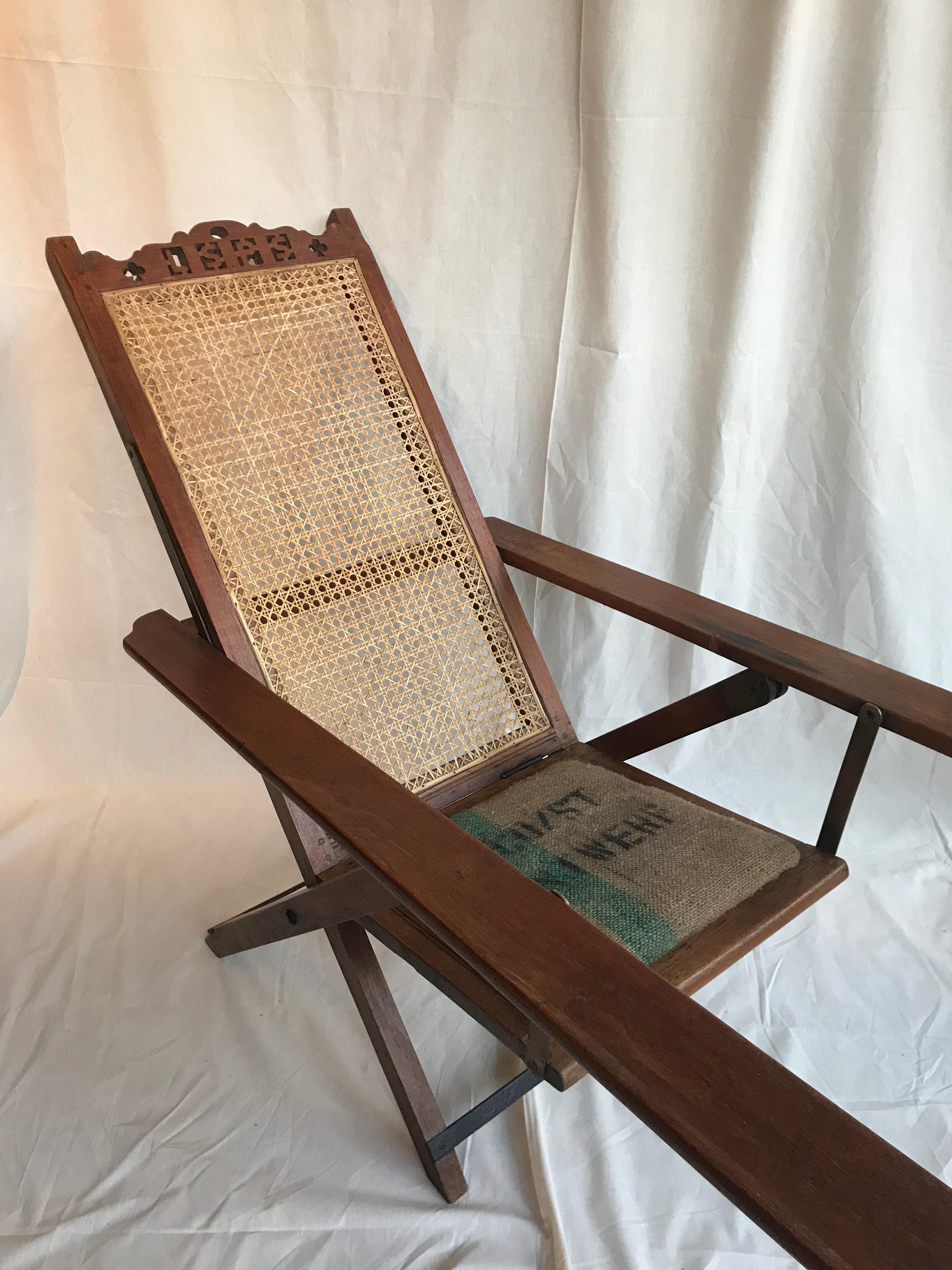 An unusual ships deck chair of oak with woven cane back and jute upholstered seat.
The back crest is carved with the initials 