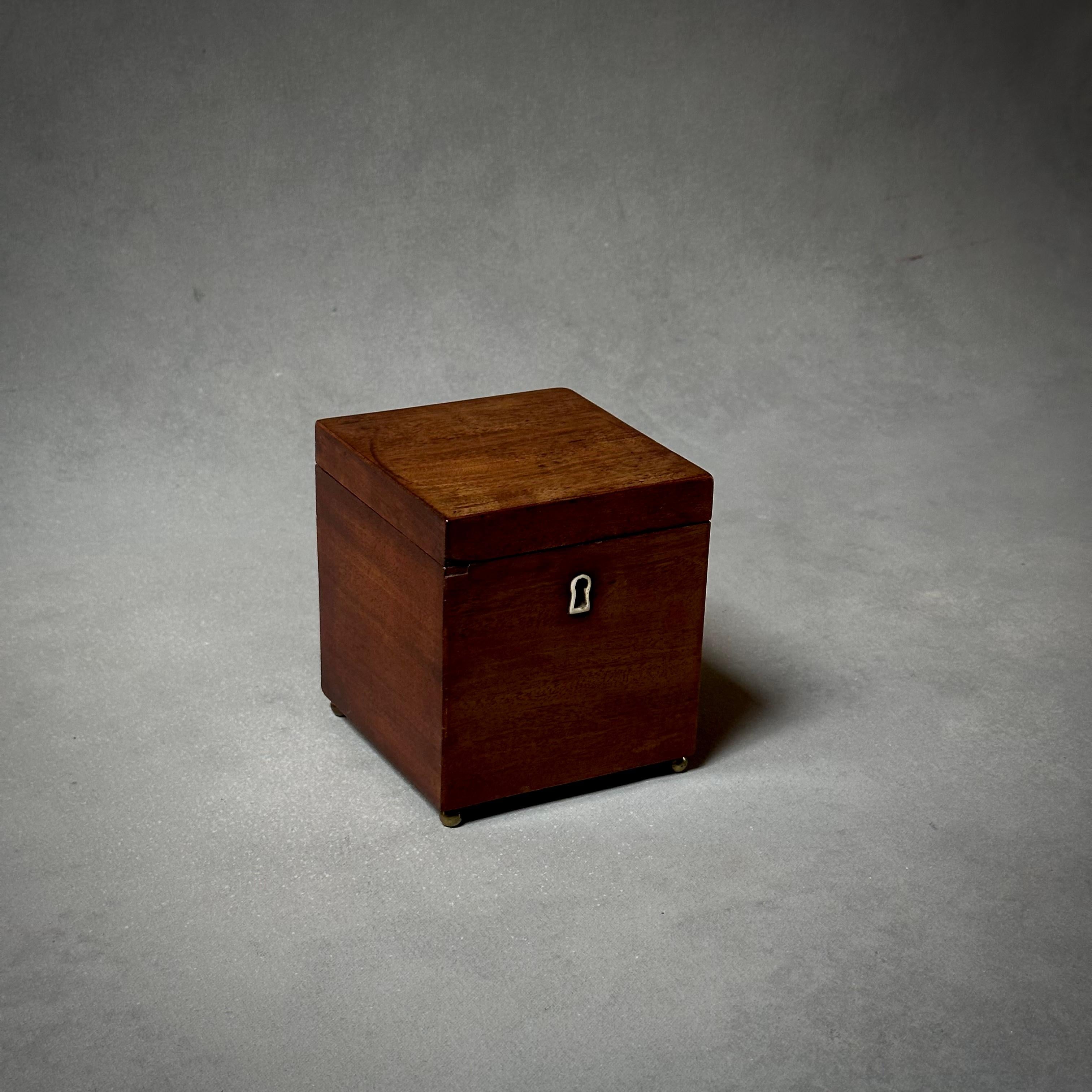 Late 19th century Belgian square mahogany tea caddy box. Features small metal keyhole and raised casters. Notable for its simple, elegant lines and handsome, timeless appeal. Would make a wonderful accent piece and storage container as part of any