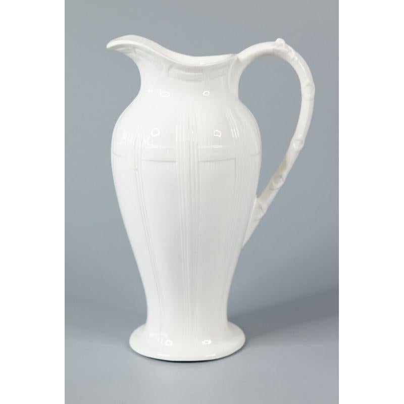 A lovely 19th-Century Belgian white ironstone pitcher. Maker's mark on reverse. It's a nice large size measuring 13.75 inches tall. This fine quality pitcher has a charming basketweave design with a bow and ribbons entwined on the handle. It would