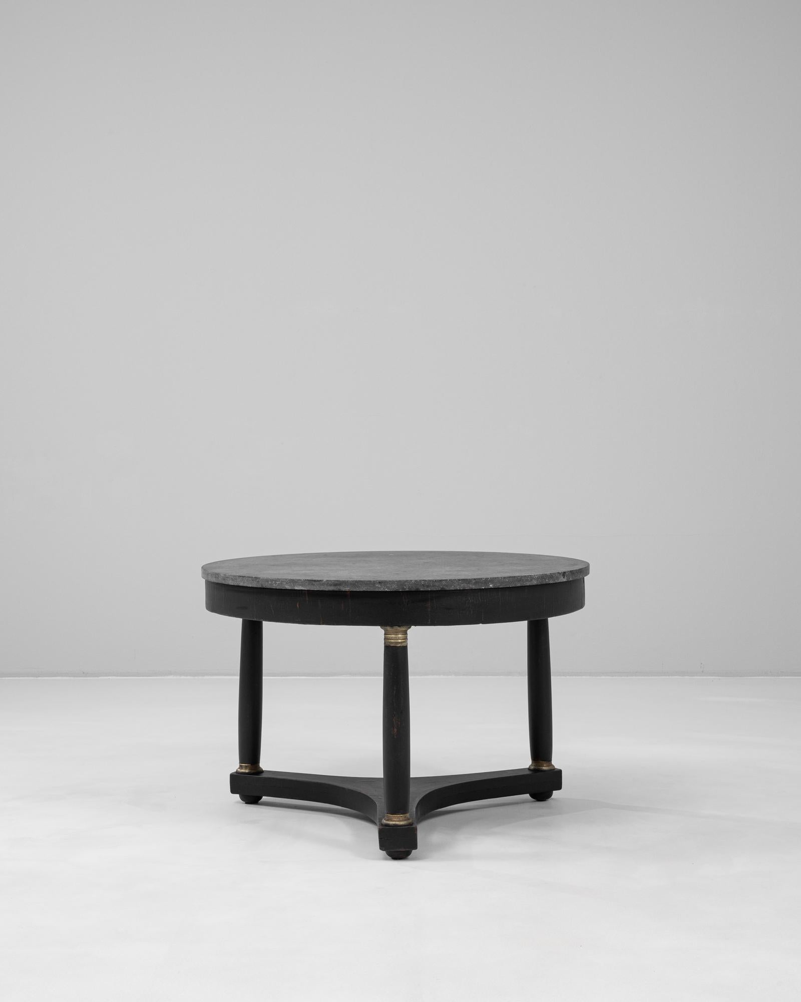 Esta mesa de centro de madera belga del siglo XIX combina una artesanía refinada con una presencia sobria y arquitectónica. La tapa redonda de mármol ofrece una superficie fresca y sustancial, y su veteado natural contrasta sutilmente con la base