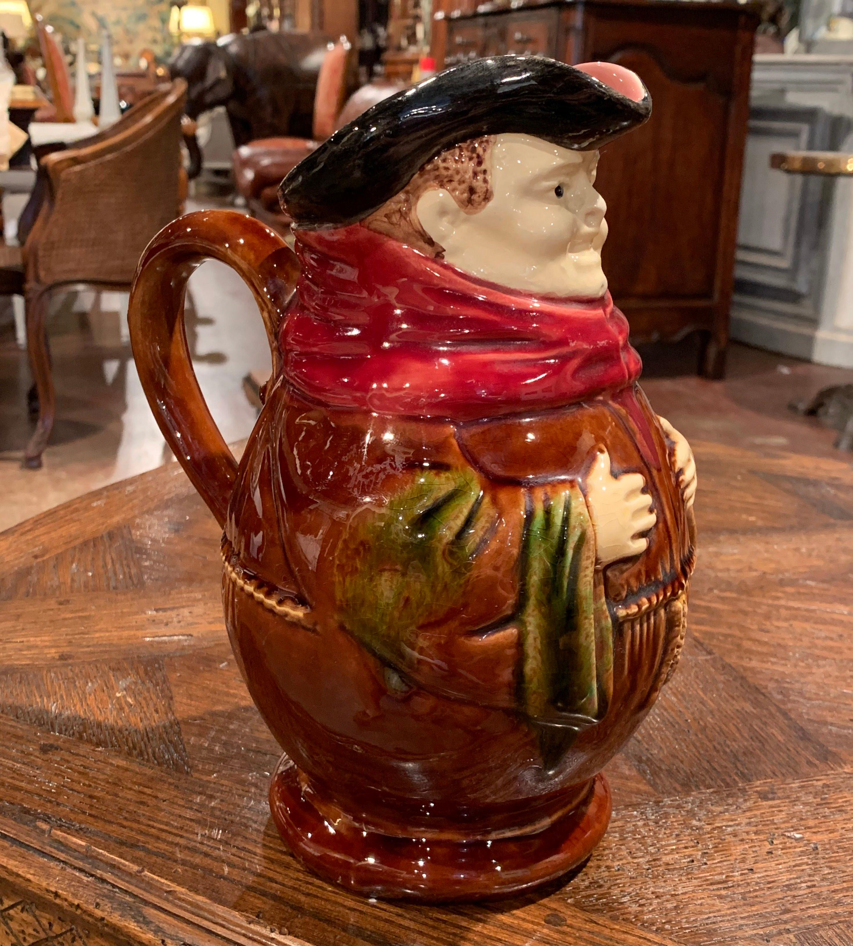 Decorate a wet bar with this charming, sculptural majolica pitcher; crafted in Nimy Les Mons, Belgium circa 1890, the antique, barbotine jug similar to the one of Onnaing, features a smiling monk with his hands on his chest in a greeting pose. The