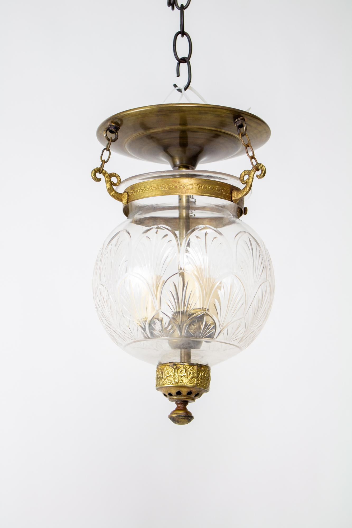 Bell jar lanterns first reached popularity in colonial India and due to their lingering popularity, production has continued to the present. Made from delicately blown clear glass with a scaled palm frond pattern. The glass is suspended by three
