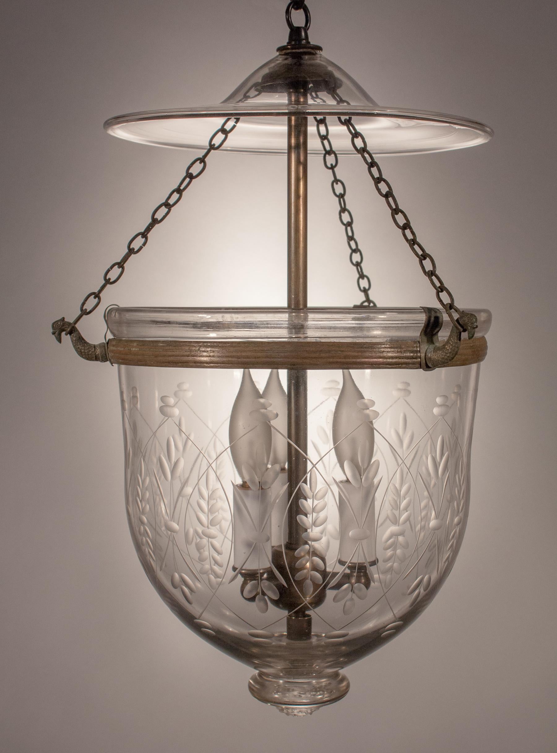 This handblown bell jar lantern boasts fullness and nice proportion for its 9-inch diameter size. The lantern has an original rolled brass band and features a finely etched wheat pattern that complements the contours of the bell jar. The pendant