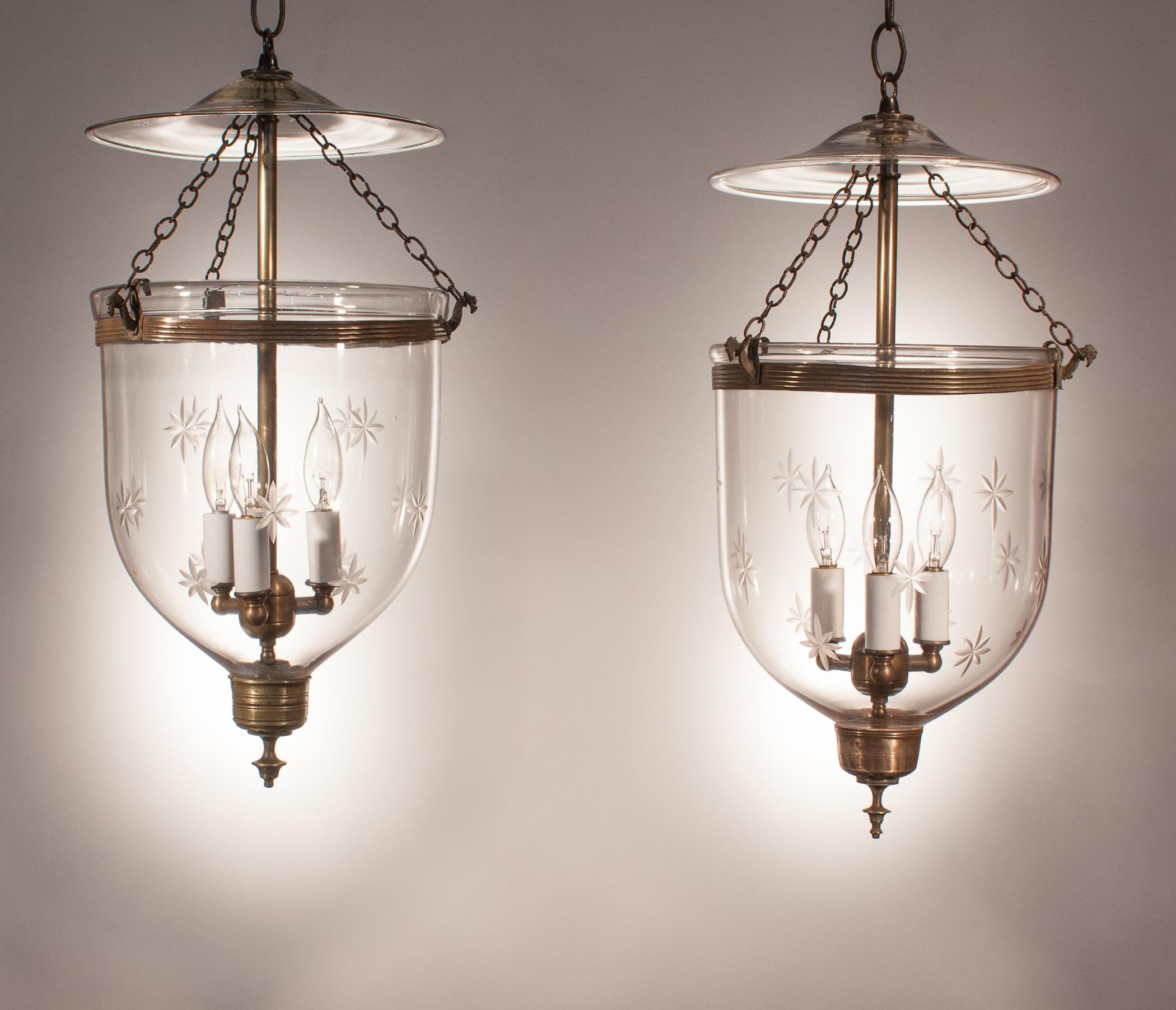 Lovely pair of antique, handblown glass bell jar lanterns with a finely etched star motif. These  hall lanterns have their original rolled brass bands and simple brass finials/candleholder bases. The finials are complementary, not identical, which