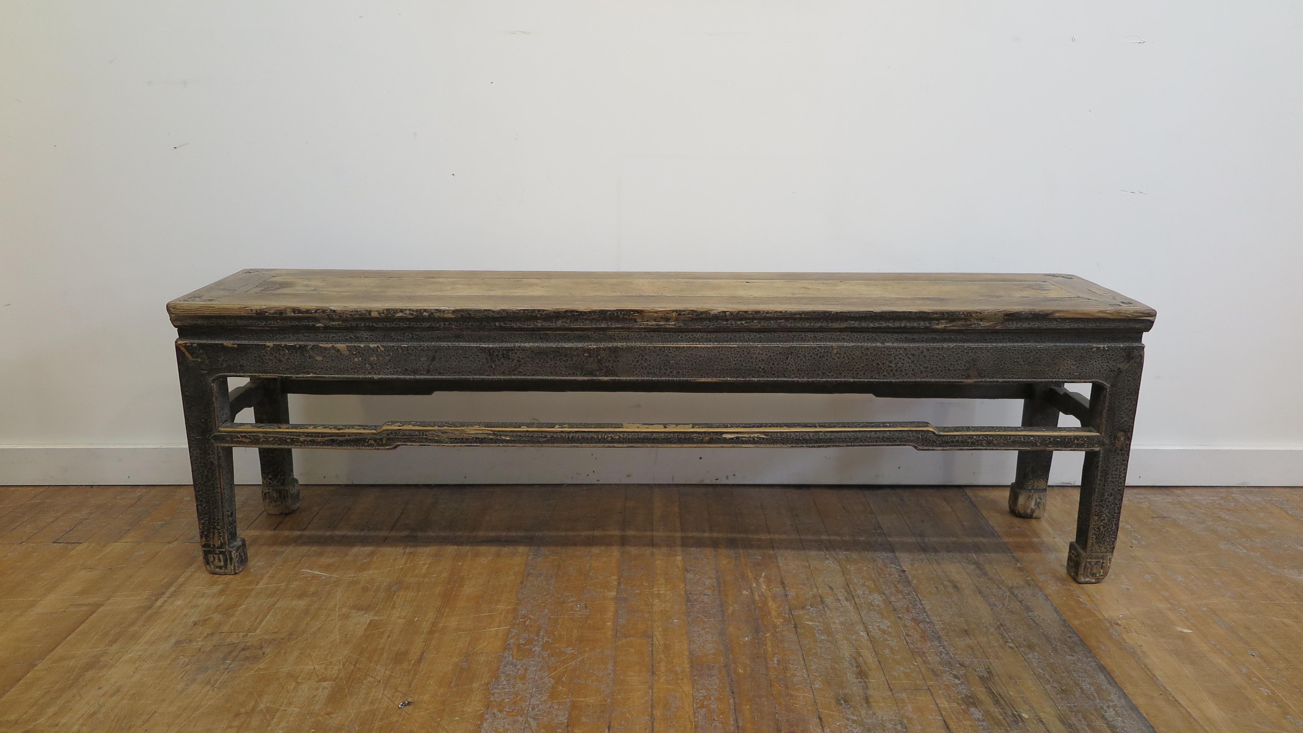 Early 19th century Chinese bench. A special black lacquered antique Elm wood bench circa 1800. A waisted (refers to specific Chinese furniture construction & joinery) raised top set on frame with hump back stretchers and struts. A most sensational