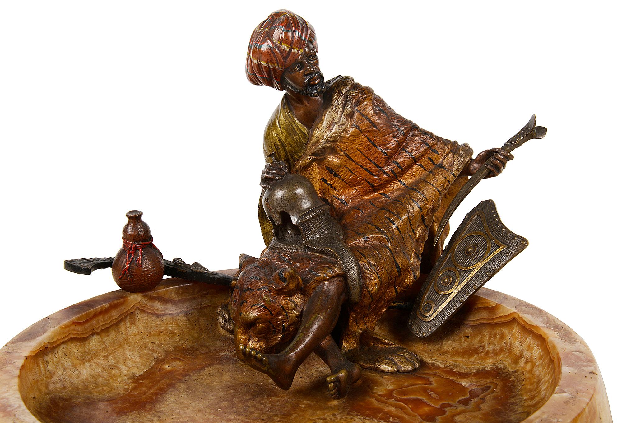 A late 19th cold painted Bergman bronze statue of a seated Arab holding a helmet, with a Tigers skin wrapped around him. Sitting on the edge of a wonderful figured marble dish.
Stamped; B . Austria.
   