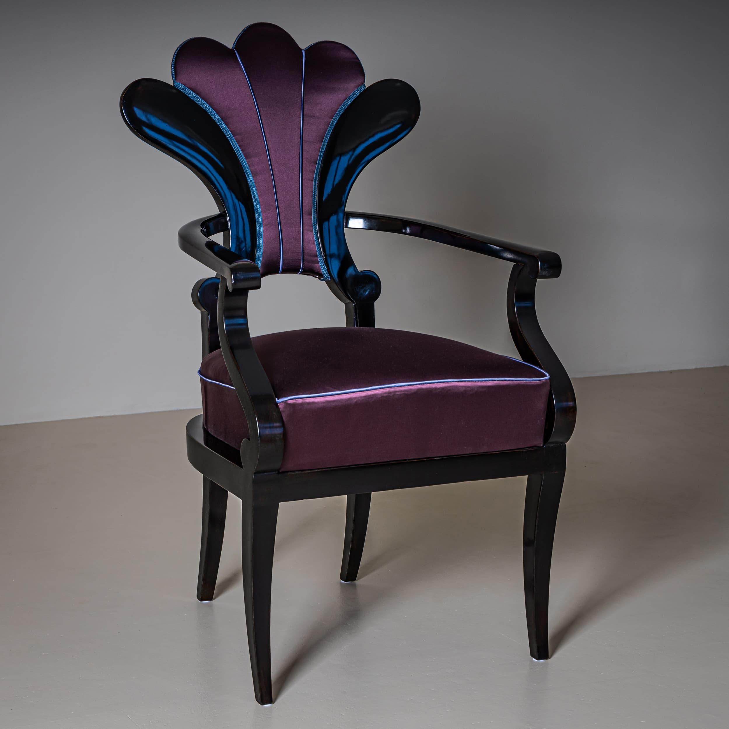 Ebonized armchair featuring a fan-shaped backrest and gracefully curved arm supports. The chair stands on tapering legs and has been newly upholstered in an aubergine-colored satin fabric with light blue piping. Expertly restored and hand-polished.