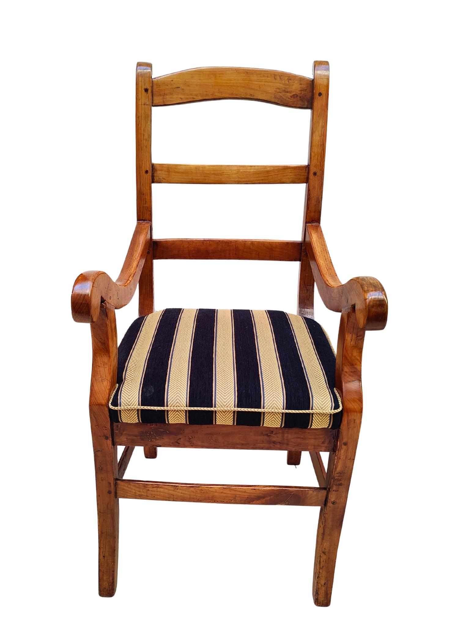 Elegante poltrona Biedermeier del XIX secolo, realizzata in ciliegio massiccio intorno al 1825. Questo autentico pezzo d'epoca mette in mostra le linee raffinate e la semplicità senza tempo caratteristiche del design Biedermeier. La cornice in caldo