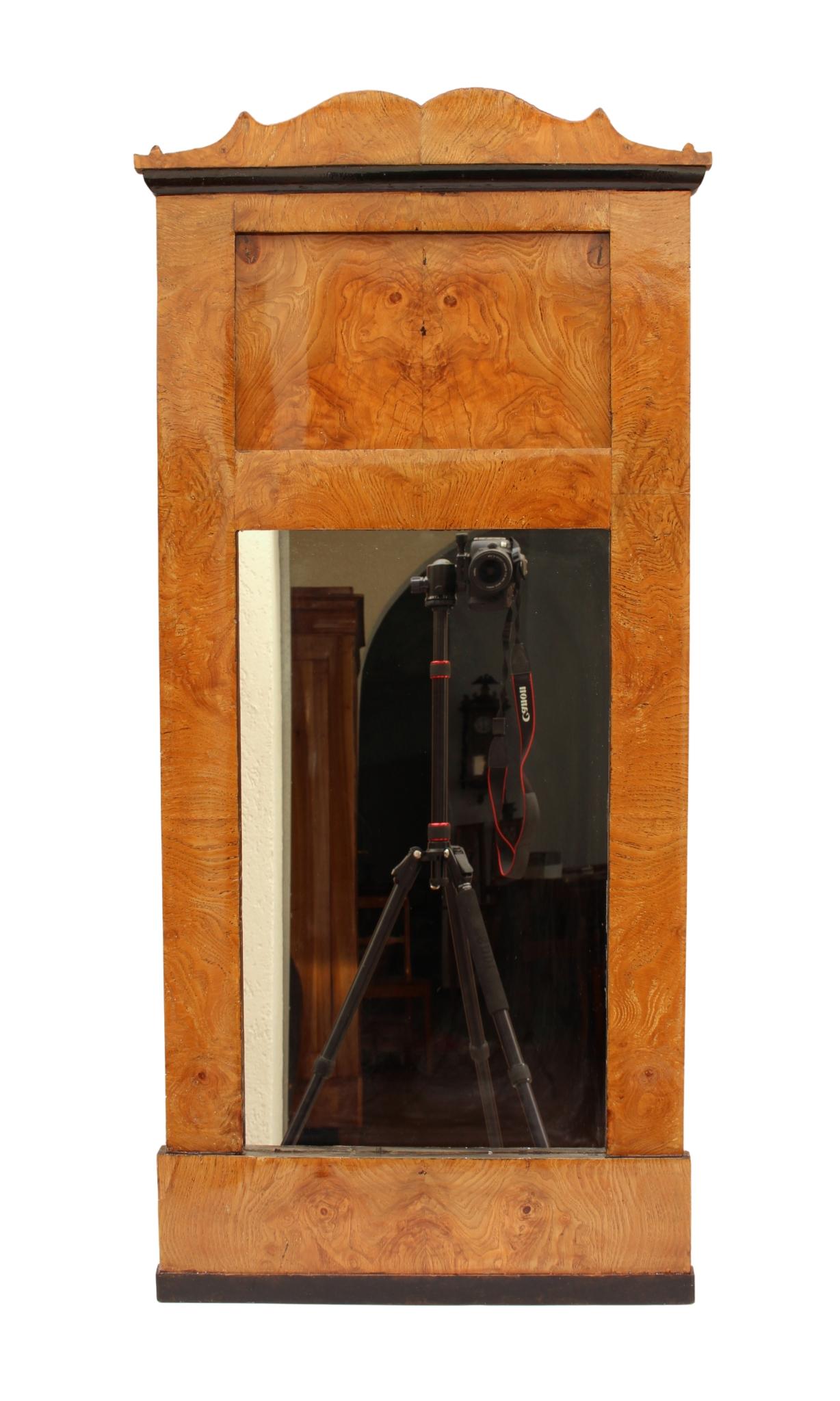 The Biedermeier mirror dates from around 1830 and was made from ash wood. The mirror has a nice medium size and a beautiful veneer pattern, the base and geison is ebonized. The mirror is in good restored condition.