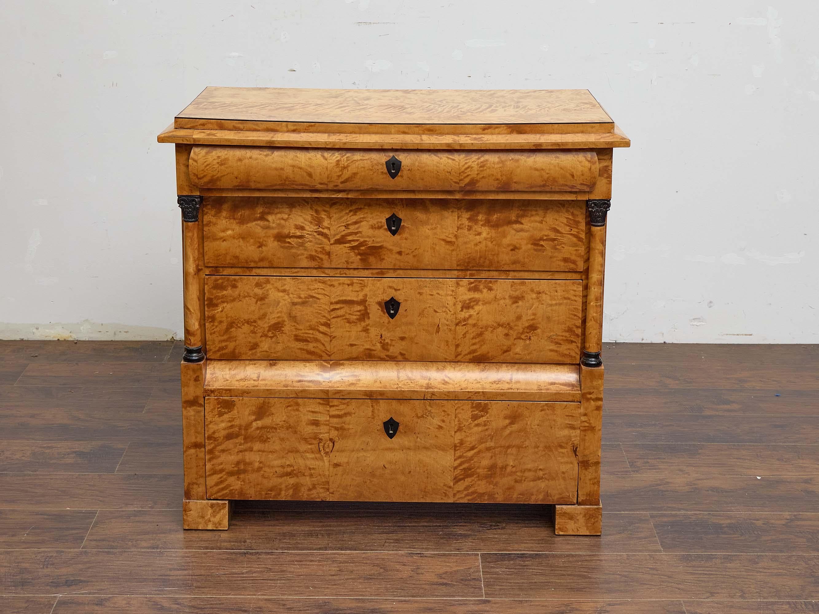 An elegant 19th century Biedermeier chest of drawers, showcasing the refined lines and understated sophistication characteristic of the period. This piece is clad in richly figured tiger maple veneer, its dramatic grain patterns lending warmth,