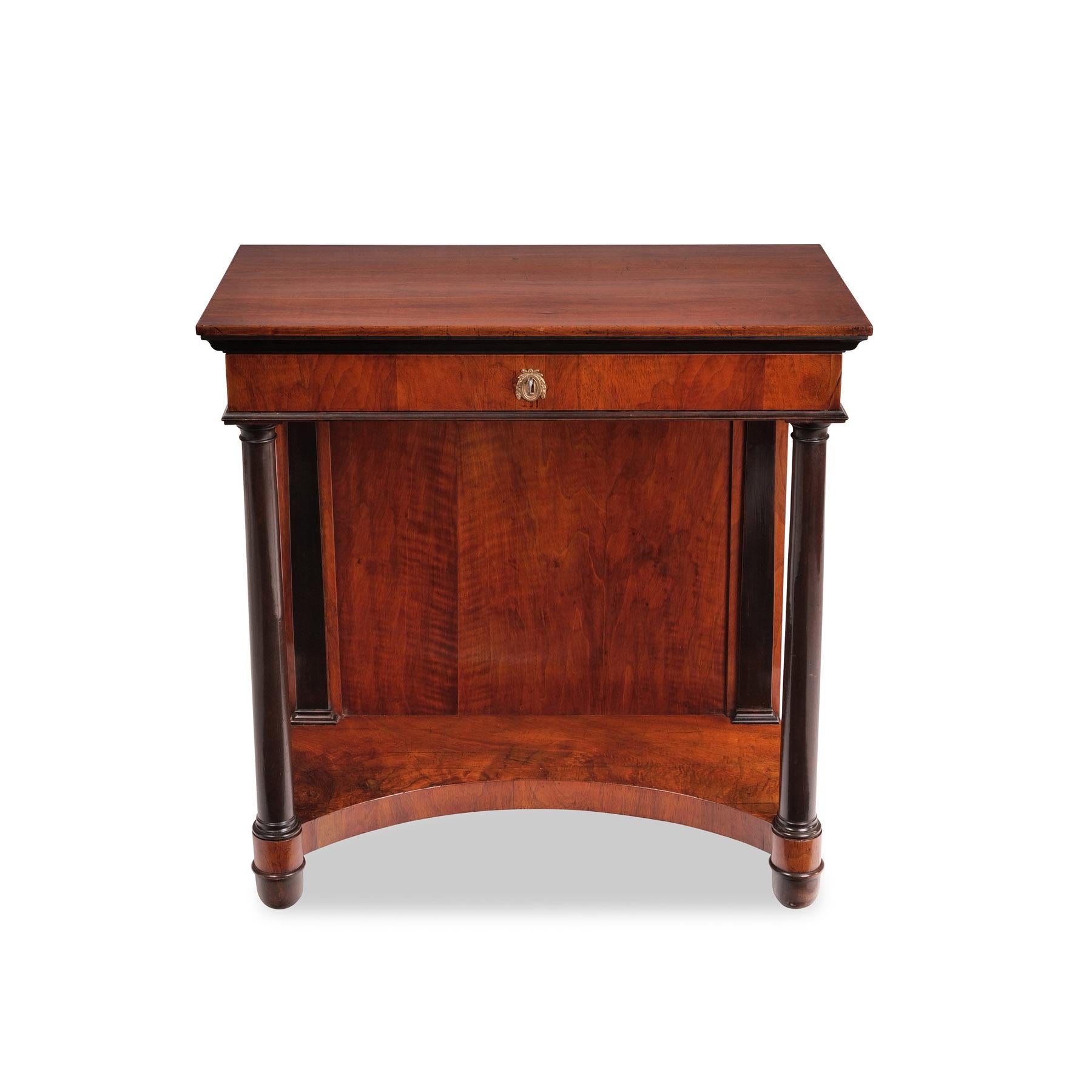 Console, Biedermeier c. 1825, mahogany, rectangular body with large drawer on two fully sculpted columns, back panel with ebonized pilasters, concave cut-out base, restored condition, shellac hand polish

Height: 89 cm, width: 86 cm, depth: 43.5