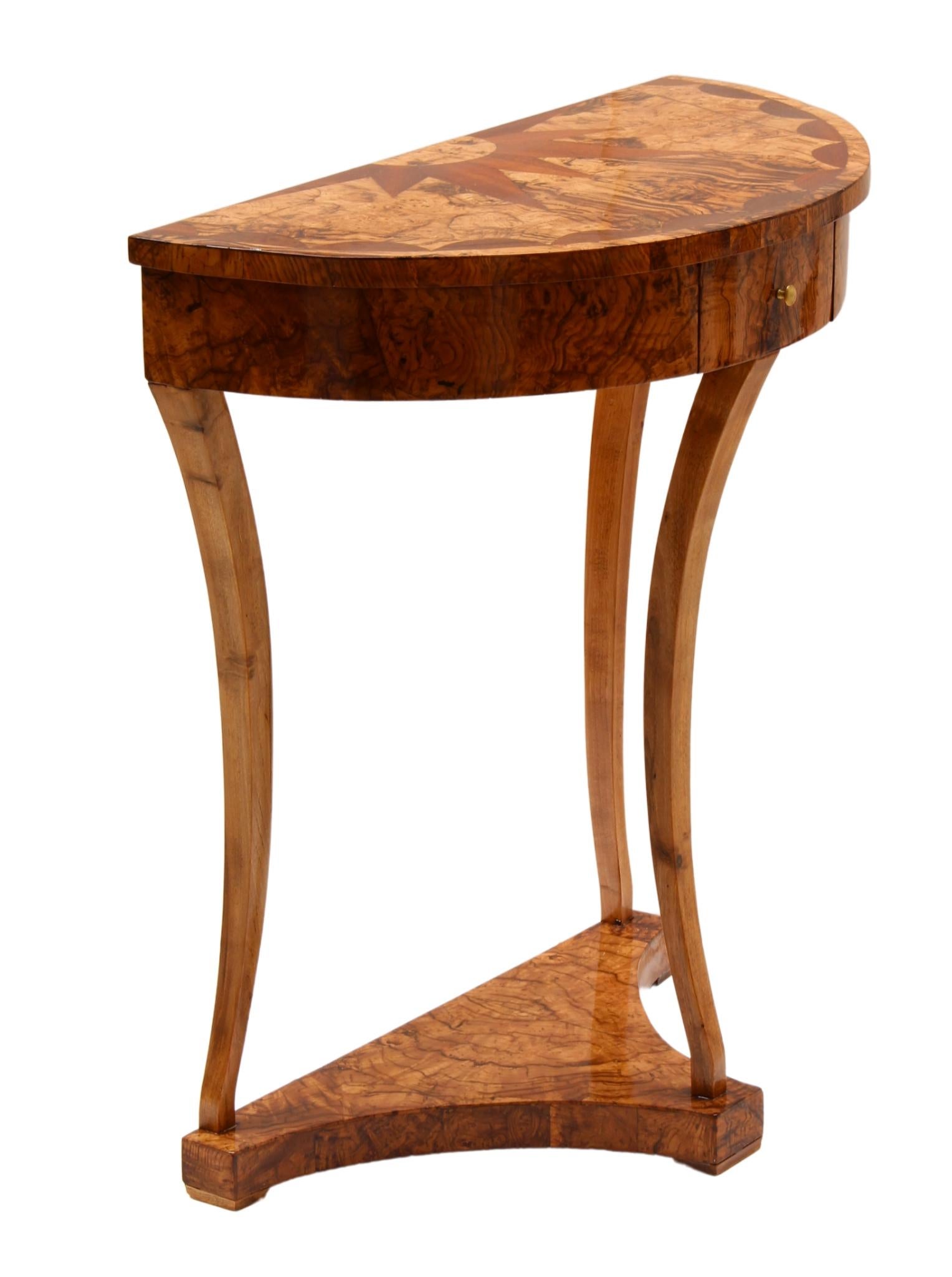The Demi Lune console dates from the Biedermeier period around 1820 and has beautiful veneer marquetry on the top. The veneer is made of ash wood / ash root wood and the legs are made of solid walnut. The console has a wonderful Biedermeier design