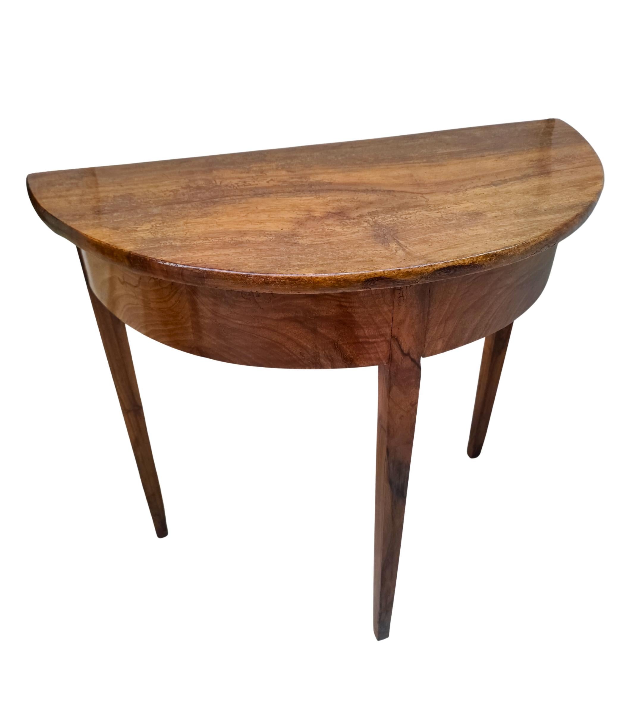 This elegant Biedermeier demi-lune console table was crafted in Southern Germany around 1820 and represents the pure, balanced design of the early 19th century. The table features a beautifully curved half-moon shape with a solid walnut top and a