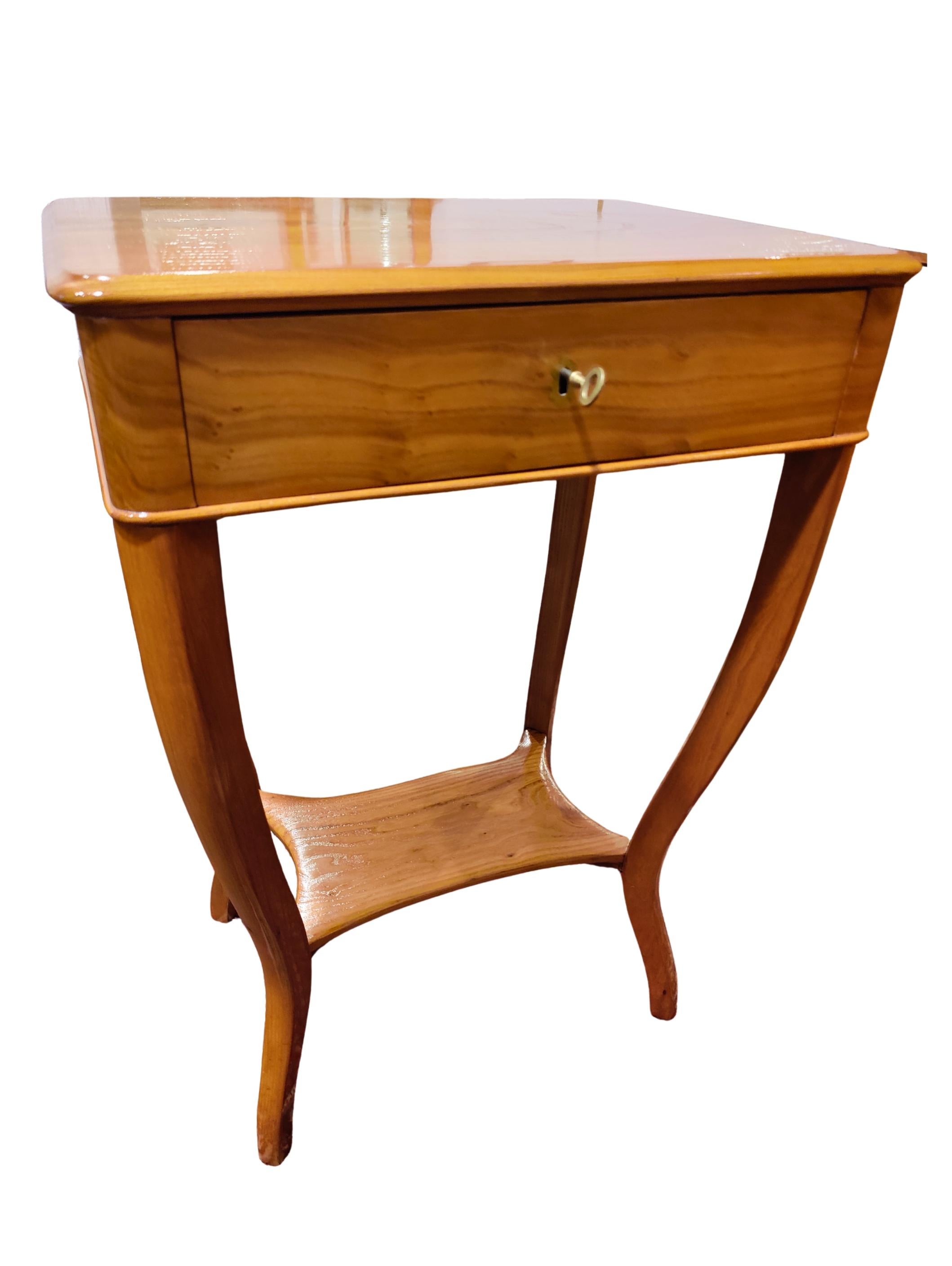 This elegant Biedermeier sewing or side table from Southern Germany, circa 1820, is crafted from beautifully grained elmwood with an interior division made of cherrywood, showcasing refined early Biedermeier craftsmanship and careful cabinetmaking