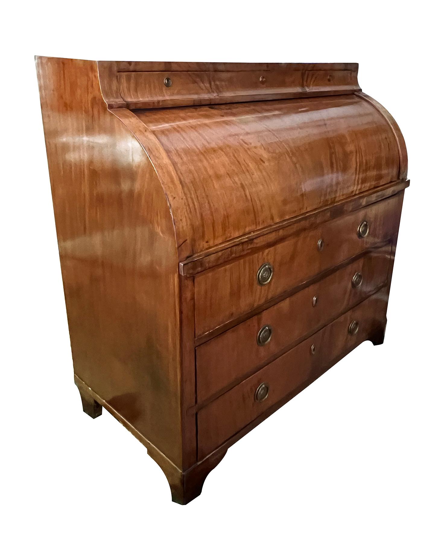 A good north Germany (possibly Hamburg) Biedermeier Cylinder Bureau overall of beautifully figured mahogany veneers; as the writing surface is pulled outward the cylinder top opens to reveal various burlwood drawers and a central arched compartment