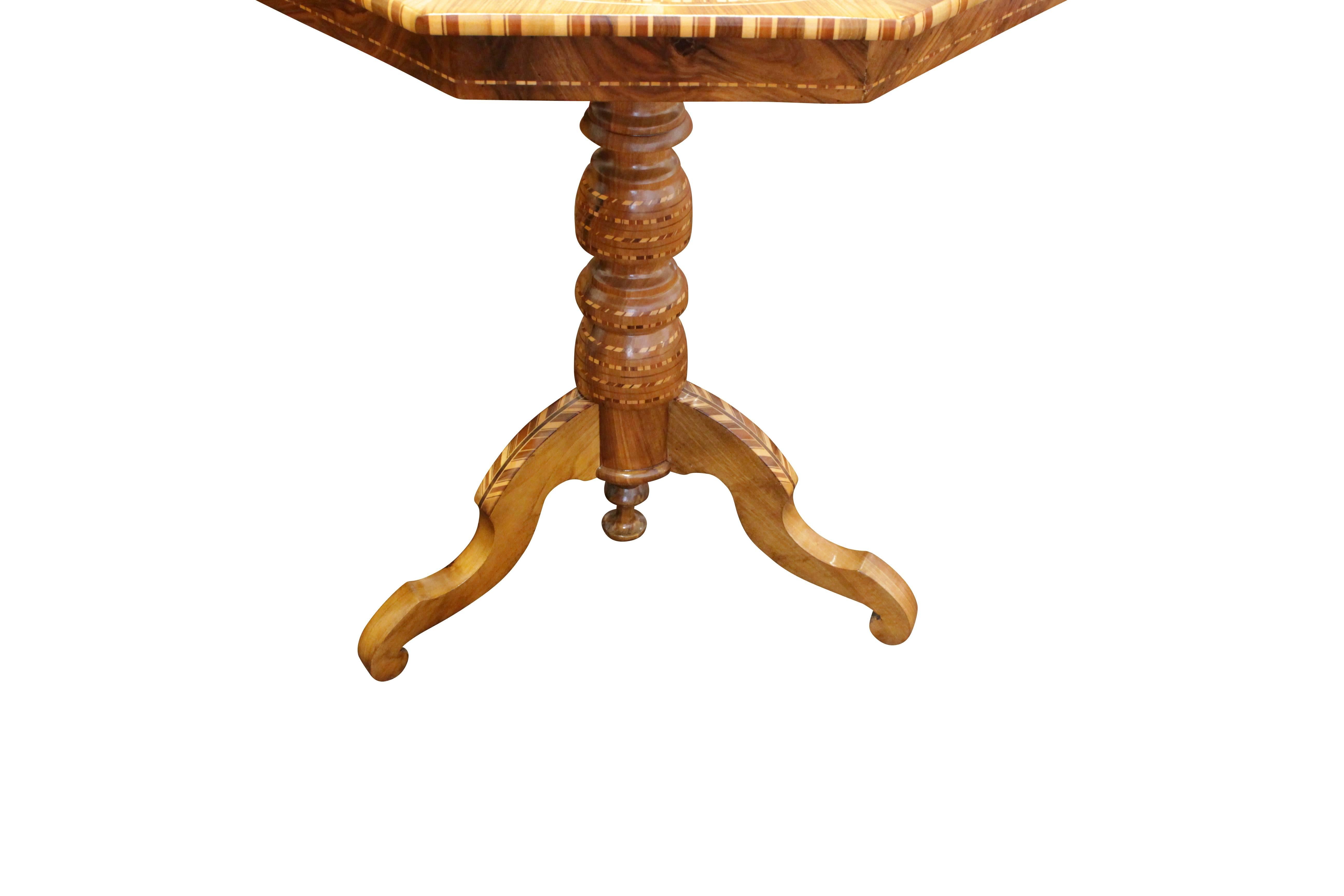 The walnut table stands on a central baluster column which itself rests on four booms at the bottom. On the tabletop is a very beautiful marquetry work. The table has been restored lovingly, and the condition is very good.