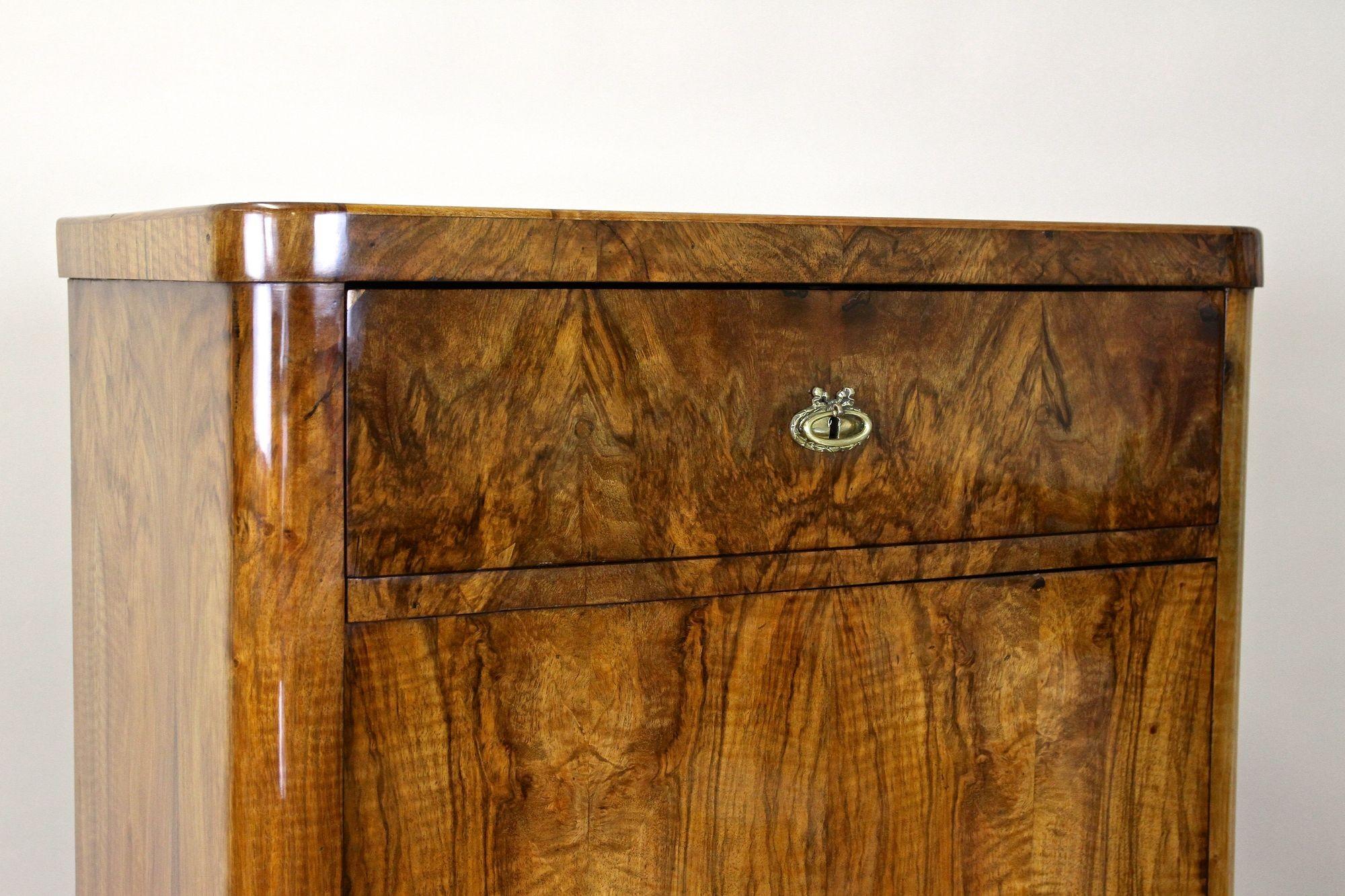 Charming 19th century Biedermeier nutwood cabinet from the famous period in Austria around 1850. Adorned by a fantastic looking mirror matched nutwood veneer work, this antique cabinet provides a large lockable door keeping the still original lock