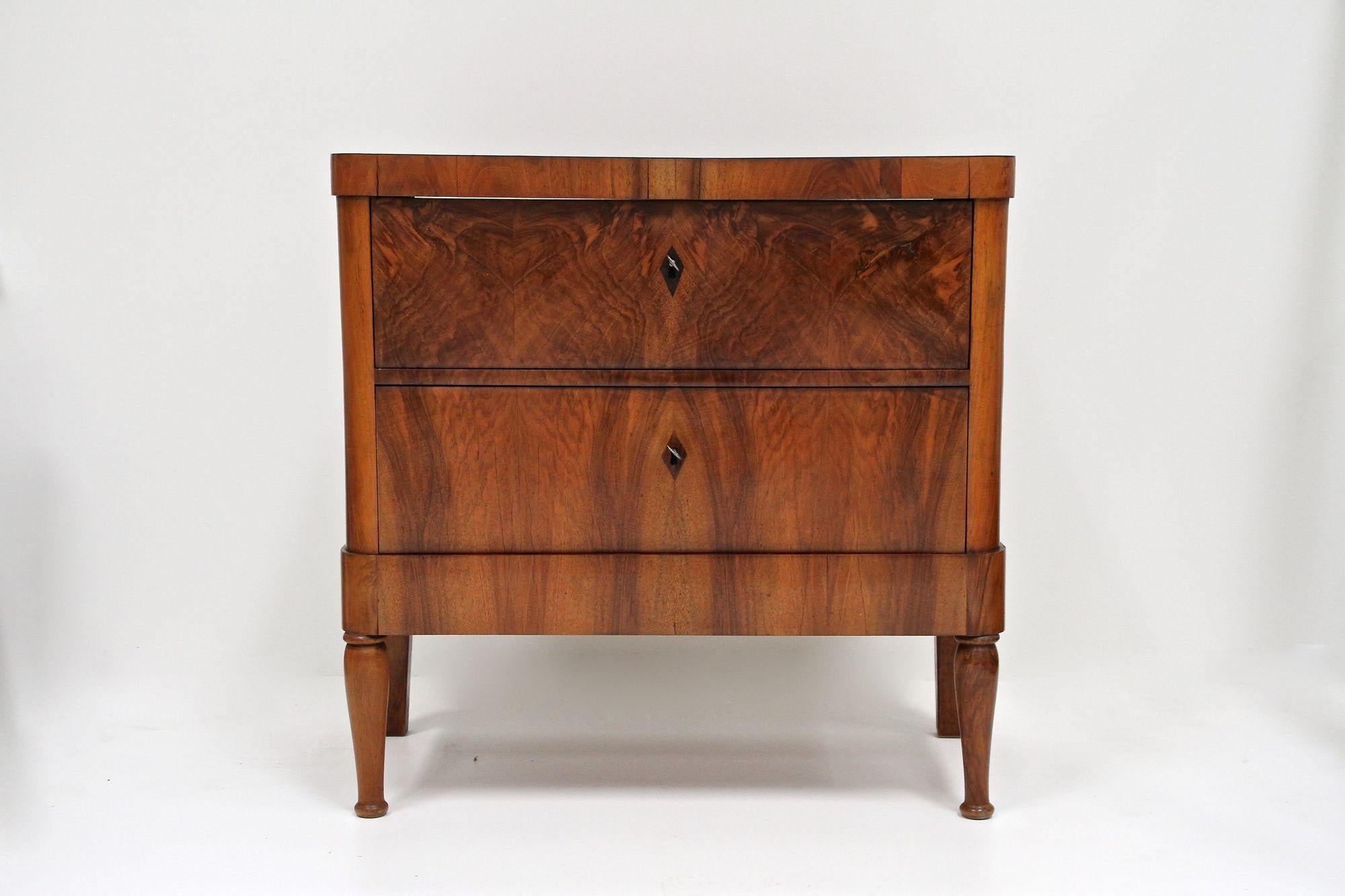 Graziosa cassettiera in legno di noce Biedermeier del XIX secolo, risalente al rinomato periodo austriaco del 1840 circa. Questa elegante commode, risalente a quasi 190 anni fa, dispone di due ampi cassetti, splendidamente impiallacciati con legno
