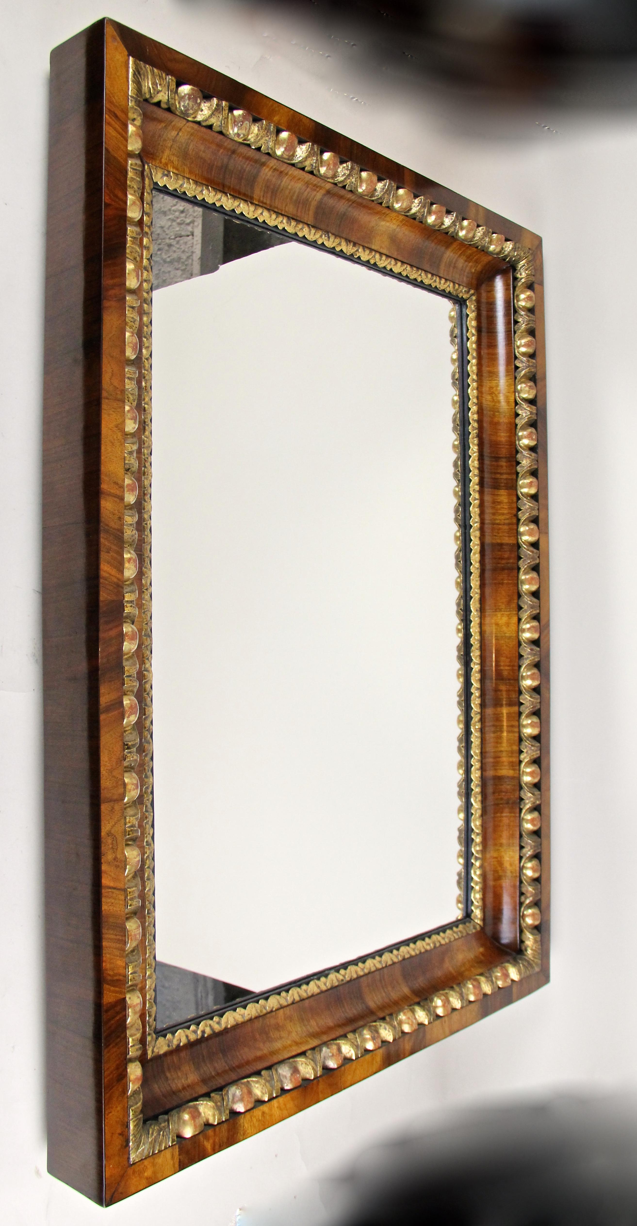Fantastic early 19th century wall mirror from the famous Biedermeier period in Vienna/Austria around 1820. Featuring an overlapping inserted substructure made of spruce, the massive, deeply grooved frame shows an amazing set walnut veneered surface