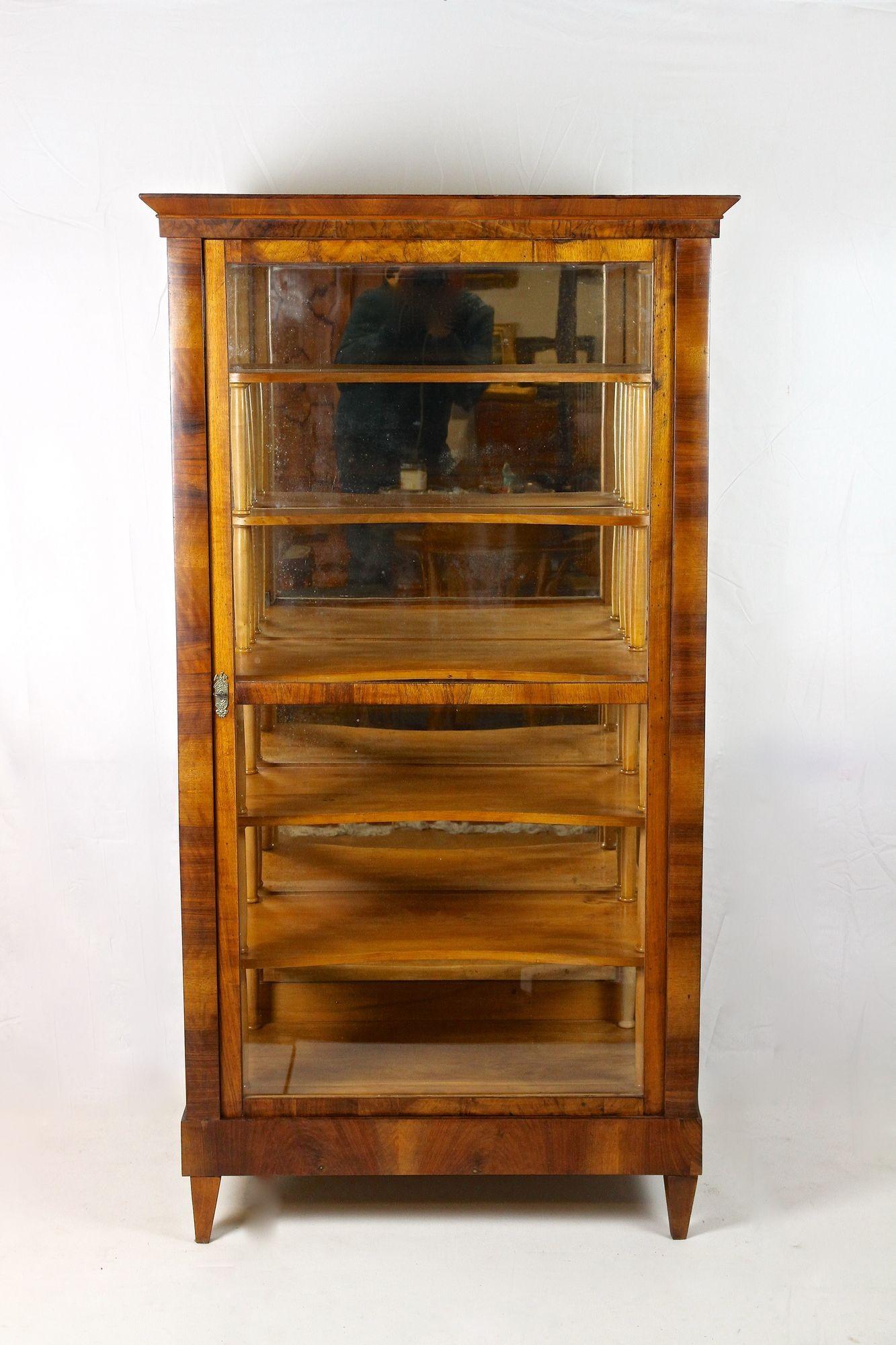 Notevole vetrina in legno di noce del XIX secolo, risalente al famoso periodo Biedermeier in Austria, intorno al 1840. Impiallacciata in pregiato legno di noce, questa bellissima teca Biedermeier colpisce per il suo grande design e per il piacevole