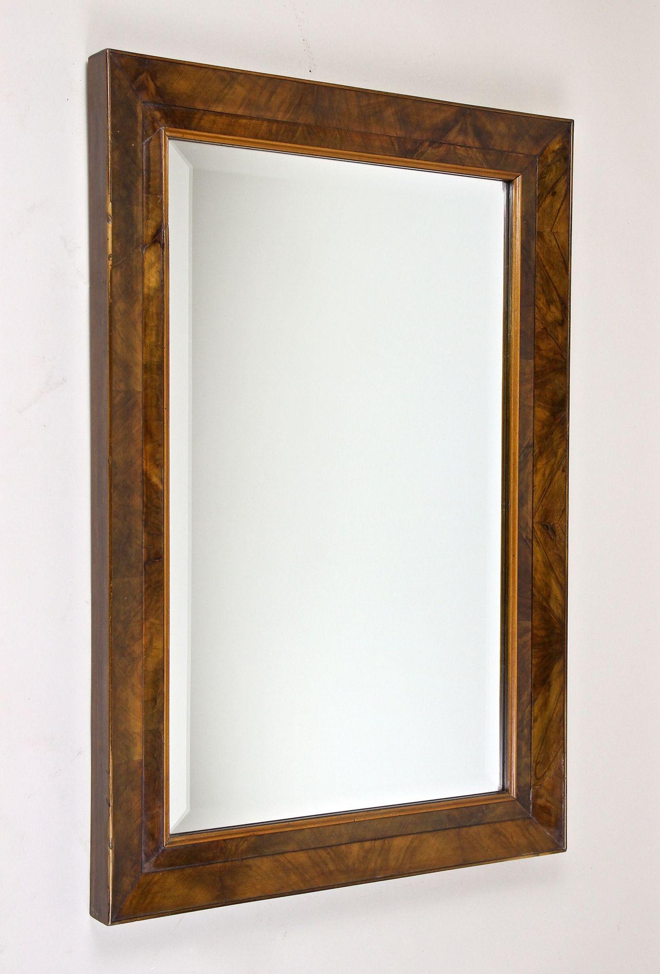 Beautiful Austrian Biedermeier nutwood wall mirror with facet cut mirror from the early period in Vienna around 1830. This lovely 19th century wall mirror shows a classical substructure made of spruce wood, veneered with fine nut wood and sealed