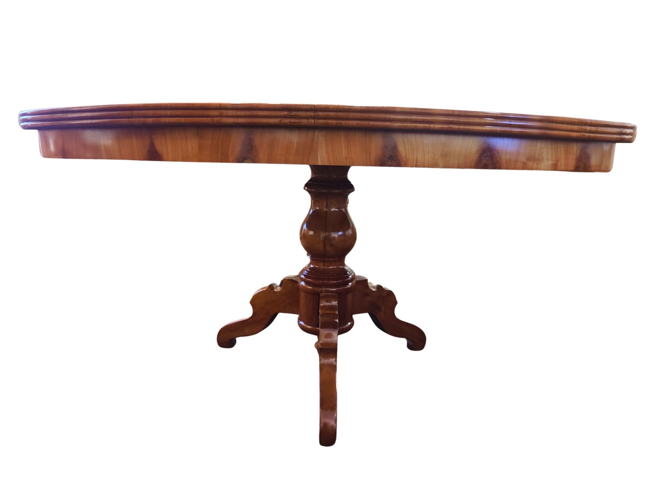 Elegante mesa de comedor ovalada de finales del periodo Biedermeier, fabricada en el sur de Alemania hacia 1830.
La mesa presenta un tablero de madera maciza de cerezo finamente veteado con un cálido tono miel y una columna central bellamente