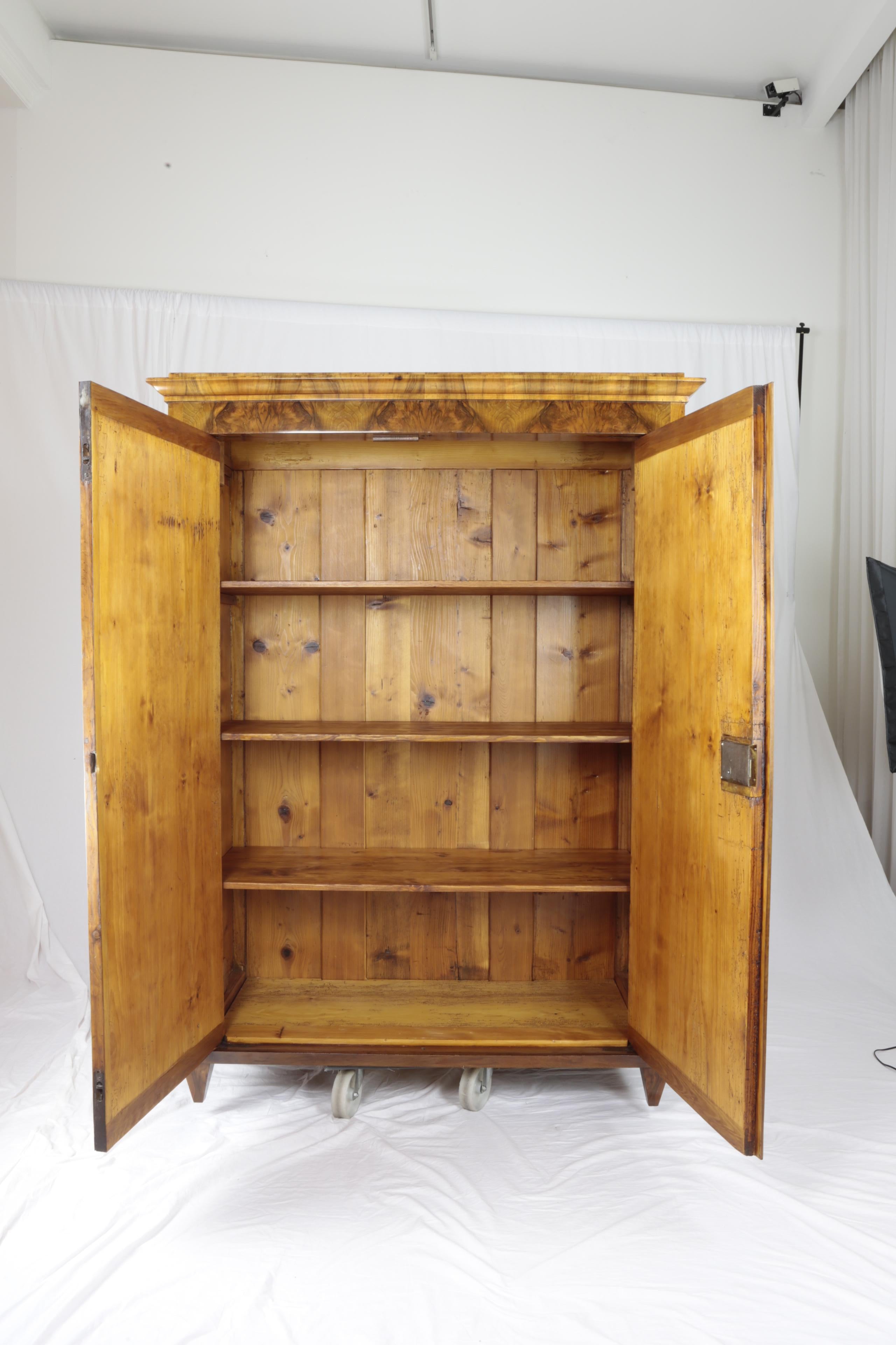 Beautiful two-door Biedermeier period cabinet with harmonious proportions, circa 1830, nutwood veneer, shelved interior, restored condition, shellac polished surface. The beautifully mirrored veneer was carefully polished by hand with
