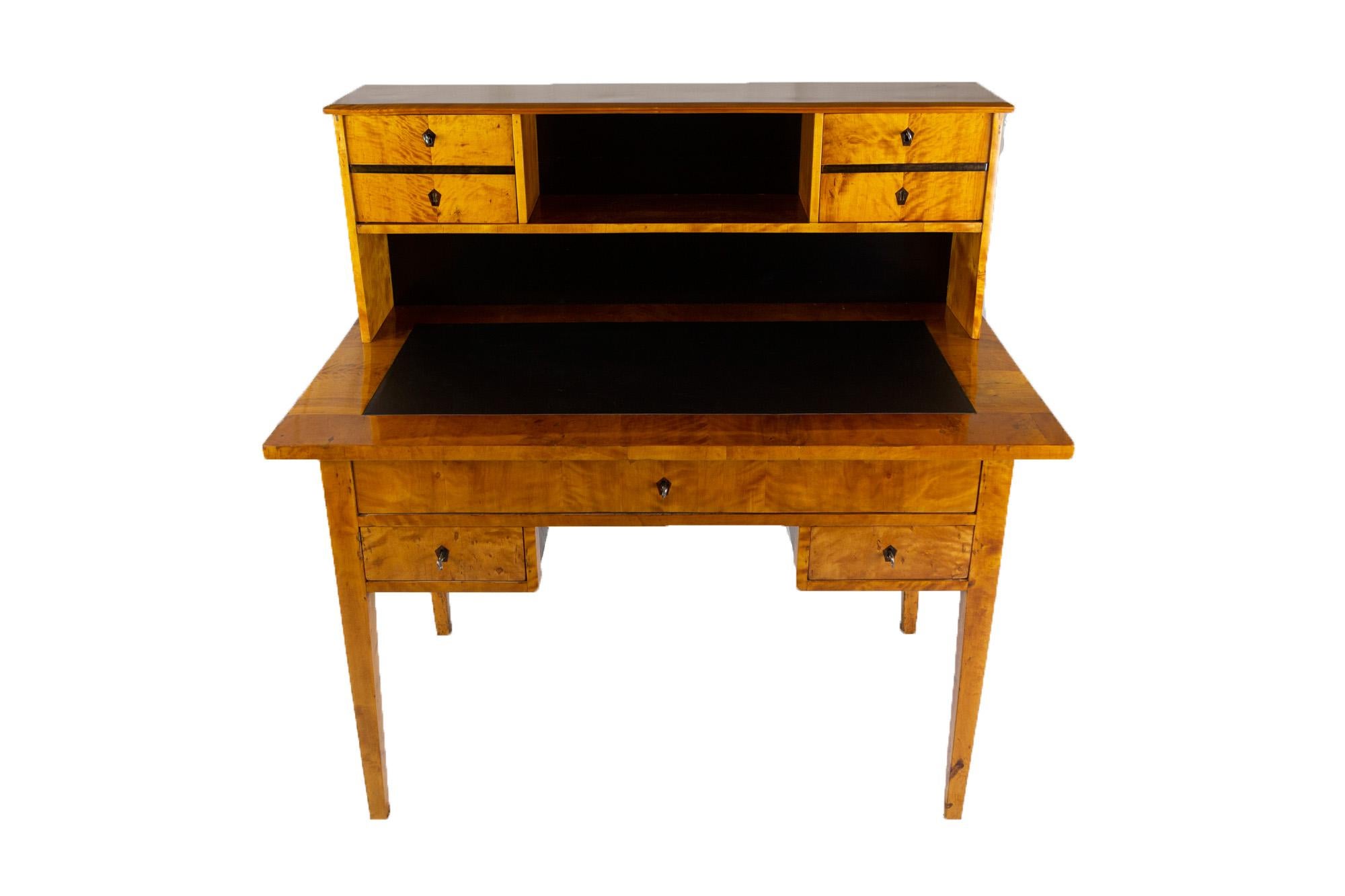 19th century Biedermeier Period writing desk in Birchwood Venner with leather inlay on the writing surface.
One middle drawer and one drawers each on the right and left side of the desk. Small attachment with two doors. 

Measures: Height 120 cm,