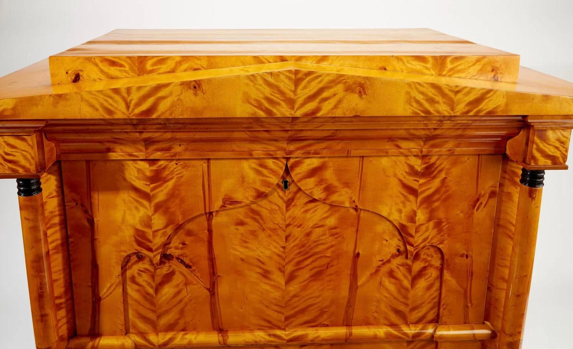 Un secrétaire Biedermeier raffiné du 19ème siècle, fabriqué en ronce d'érable et placages, mettant en valeur l'élégante simplicité de la période Biedermeier. La façade s'ouvre pour révéler un intérieur méticuleusement agencé avec des compartiments