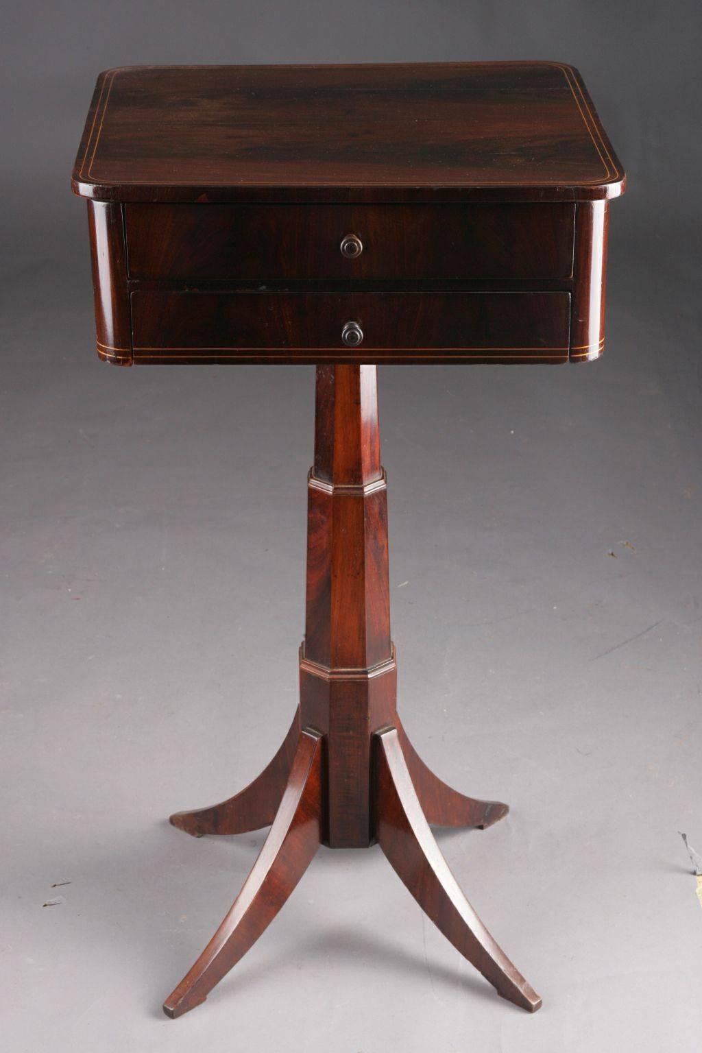 Decent Biedermeier sewing table, circa 1825.
Mahogany on solid softwood. Straight, two-handed frame box on a telescopic column on saber-shaped legs. Filament and ribbon inlays. Four-sided tabletop in compartments for sewing utensils.

(G-27).