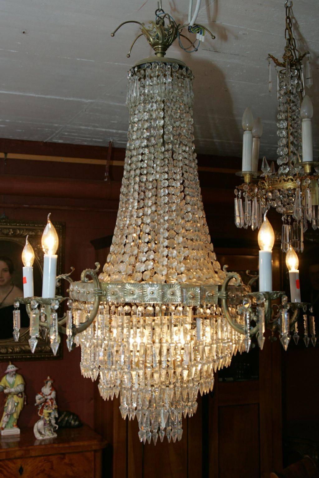 Classic antique ceiling chandelier in the Biedermeier style, circa 1900.
Brass chiseled. Baluster-shaped corpus of hand-wired, faceted glass cords. Broad luster ring outgoing five curved armor arms ending in vase-shaped grommets over round eaves.