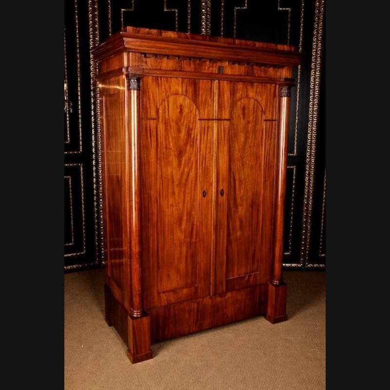 Unique Biedermeier floorboard, circa 1825.
Cuba mahogany on softwood. On the log feet high-rectangular two-door corpus with profile-framed arch-shaped fields. Architecturally arranged front with flanking full columns of solid mahogany, carved