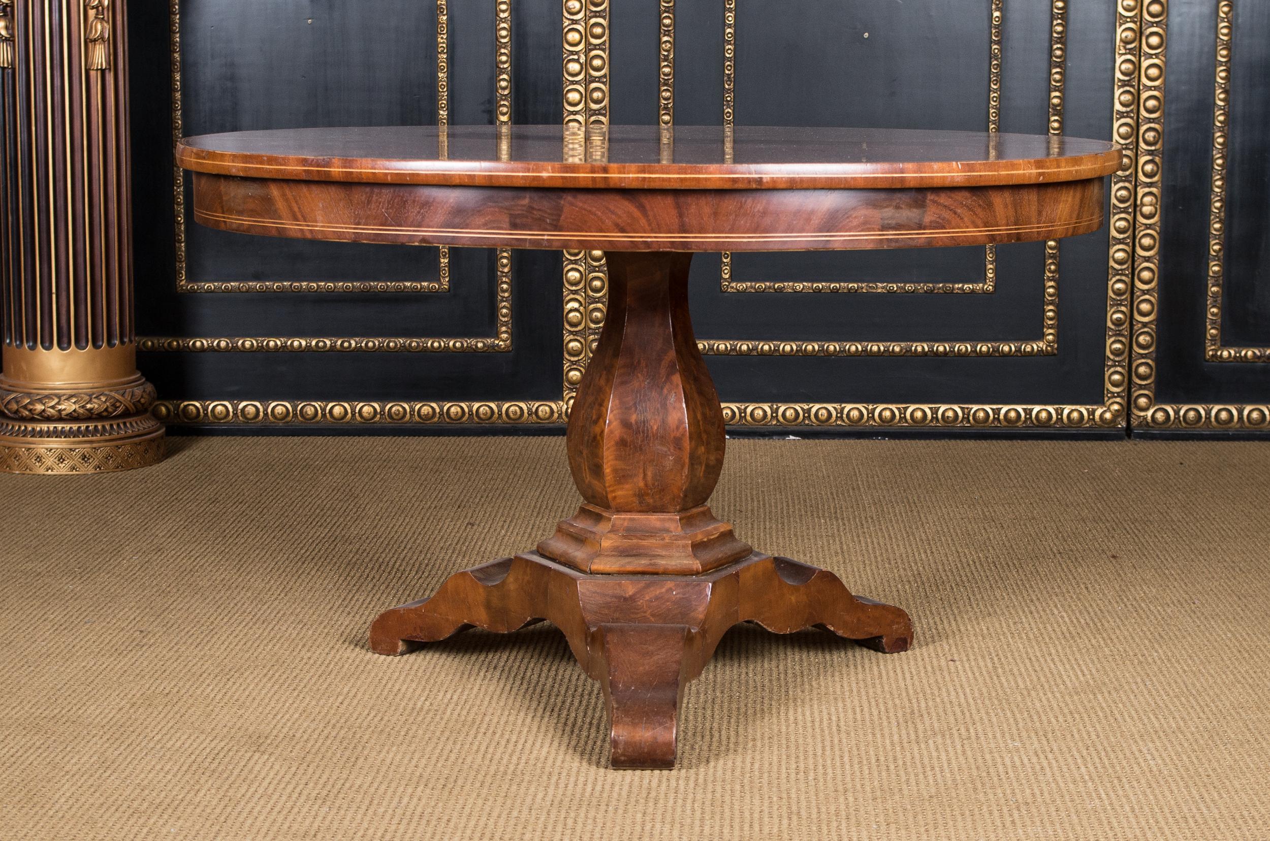 Original Biedermeier table, circa 1820. Solid softwood. Cuba mahogany veneer. Oval plate on hexagonal shaft on draw-in base plate and with three legs.