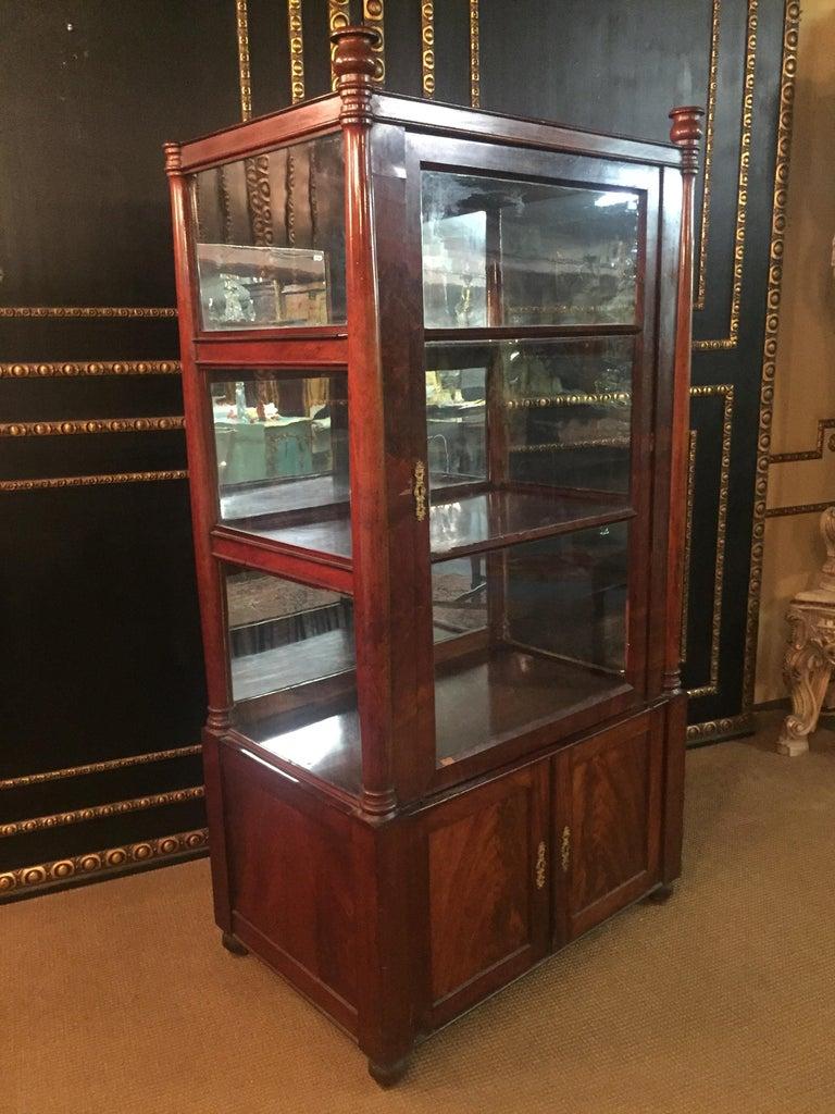 Three-sided glazed glass vitrine circa 1825 in the sense of Karl Friedrich Schinkel. High-quality Mahogany on solid softwood. Recessed frame box. Architecturally arranged front with flanking columns, Three-sided sprout-glazed corpus. Stepped