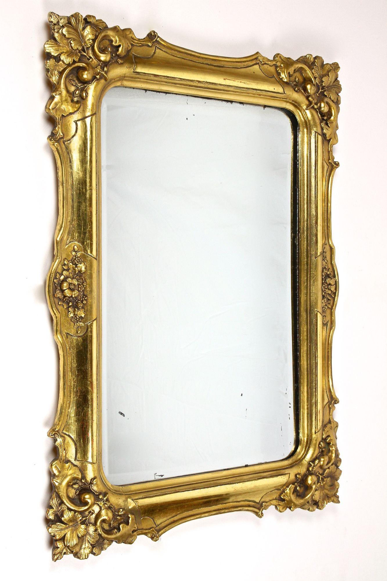 Exceptional Biedermeier wall mirror from the era around 1830 in Austria. The artfully processed, gold leaf covered frame is adorned by absolute elaborately handcarved corners depicting unique floral designs and covered by an amazing looking patina.